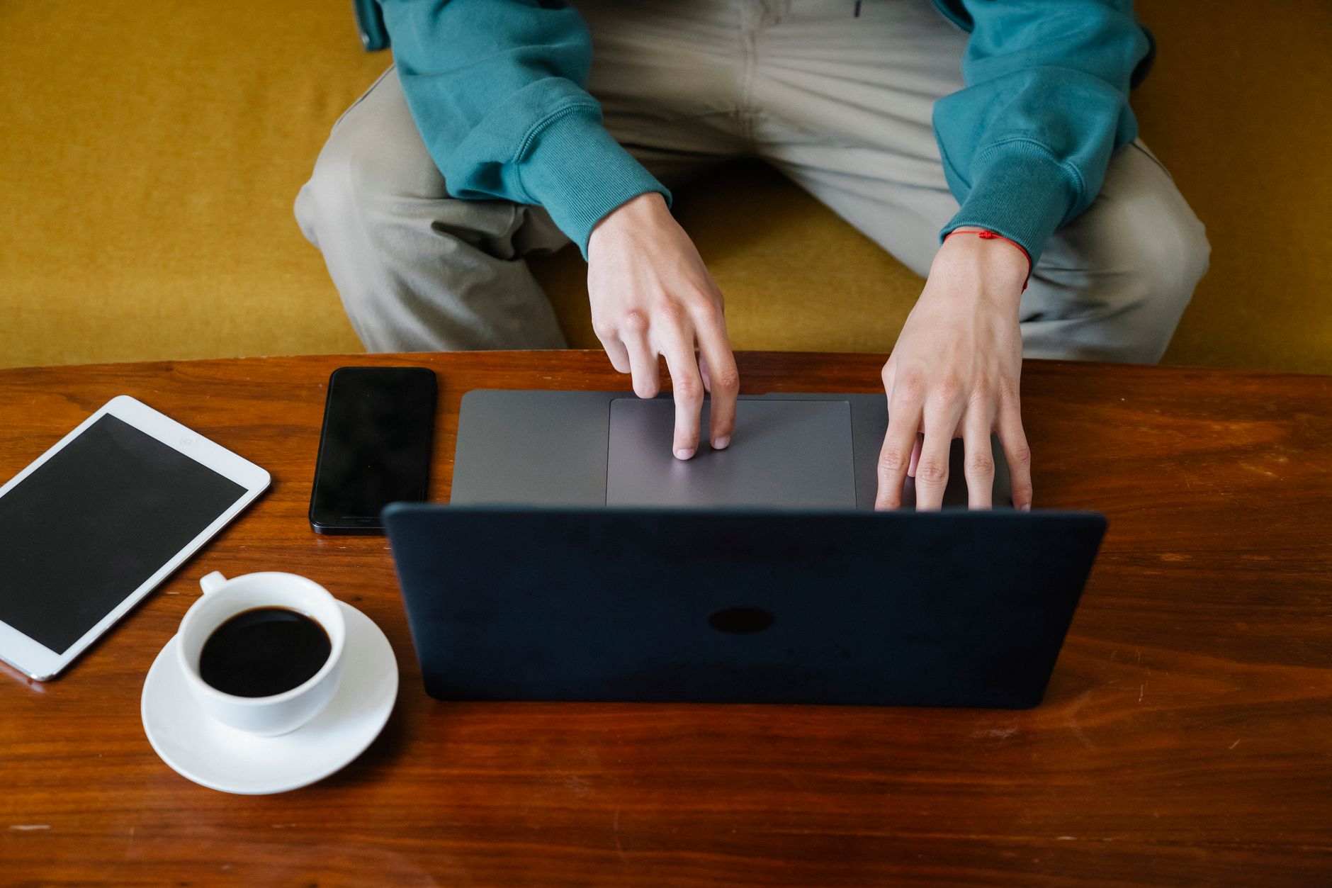 Pessoa segurando um celular grande ao lado de um tablet sobre uma mesa.