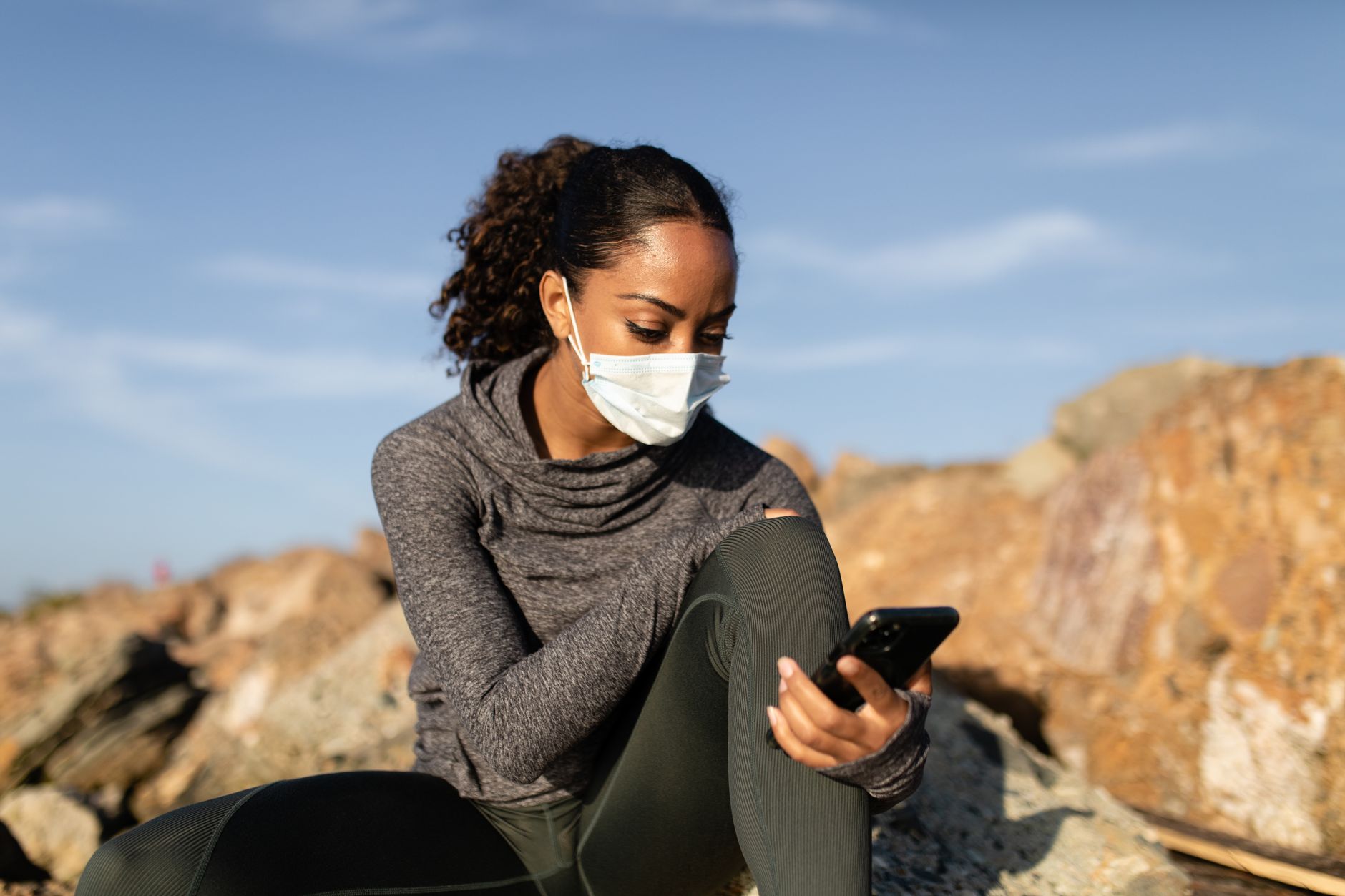 Pessoa segurando um celular protegido por capa em ambiente externo