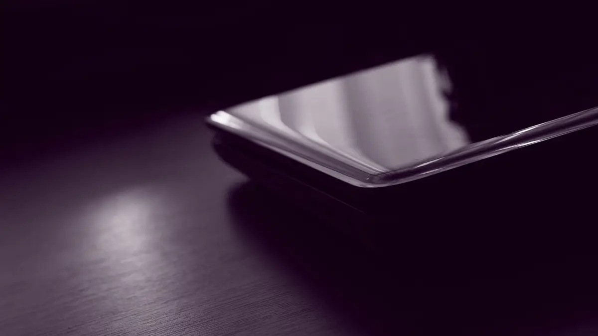 Celular preto deitado sobre uma superfície escura