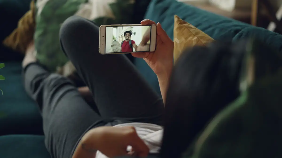 Pessoa em videochamada pelo celular apoiado em suporte na mesa
