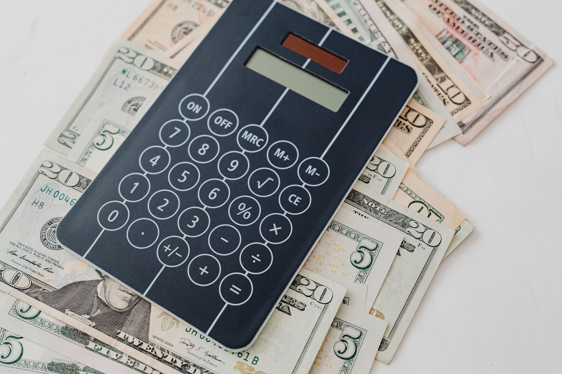 Quanto são 100 dólares em euros? Close-up of a calculator atop US dollar bills, symbolizing financial planning and budgeting.