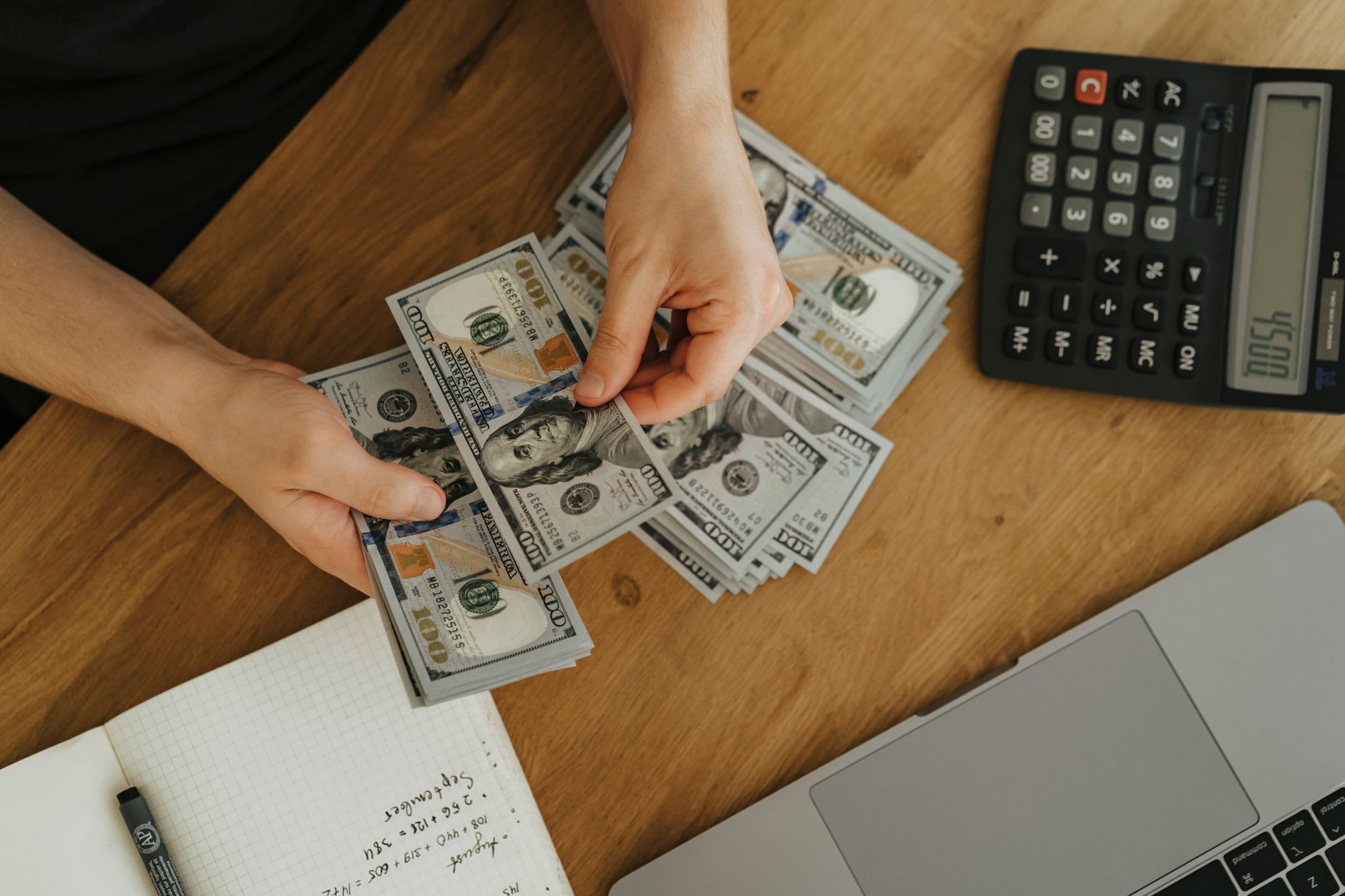 Pessoa conferindo a conversão de euros para reais em uma mesa com celular e documentos.