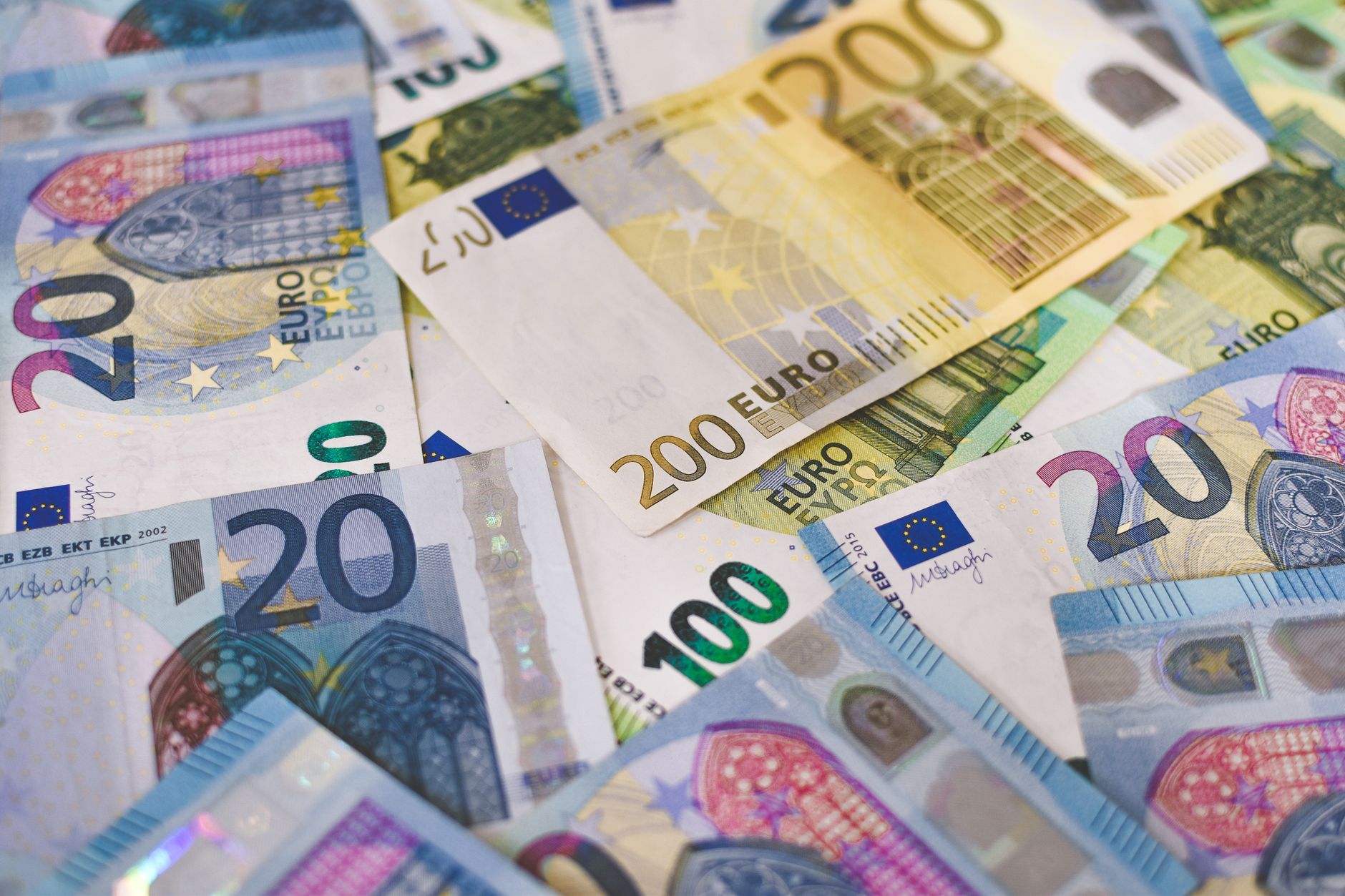 Como converter dólares em euros? Close-up of various Euro banknotes scattered on a surface, highlighting European currency.