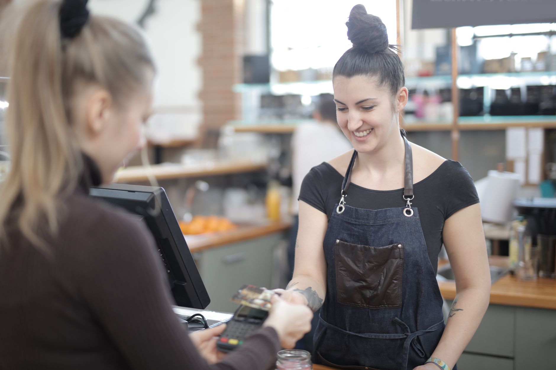 Quanto são 500 dólares em euros? Veja como converter Smiling cashier helping customer with payment at store counter.