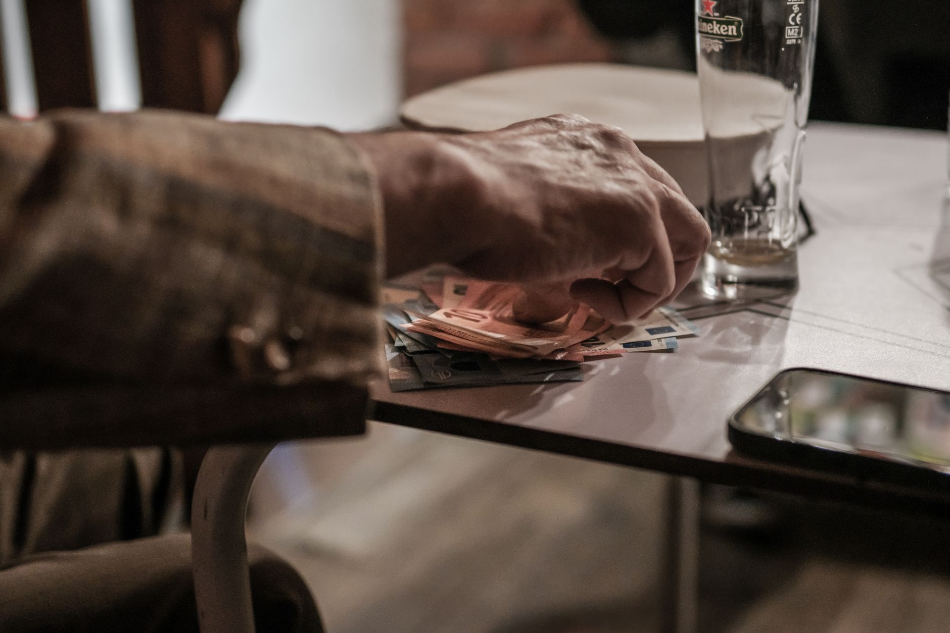 Pessoa organizando cédulas de euros sobre uma mesa de madeira ao planejar viagem.
