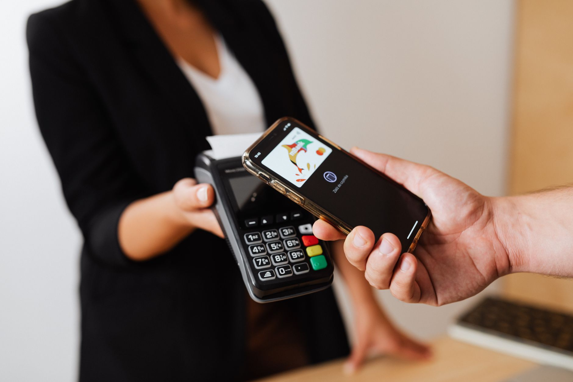 Quanto Custam 500 Euros em Reais e Como Converter A person using a smartphone for contactless payment at a retail store counter.