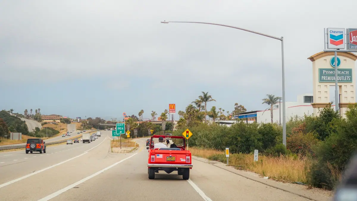 Carro conversível percorrendo uma rodovia à beira-mar na Califórnia