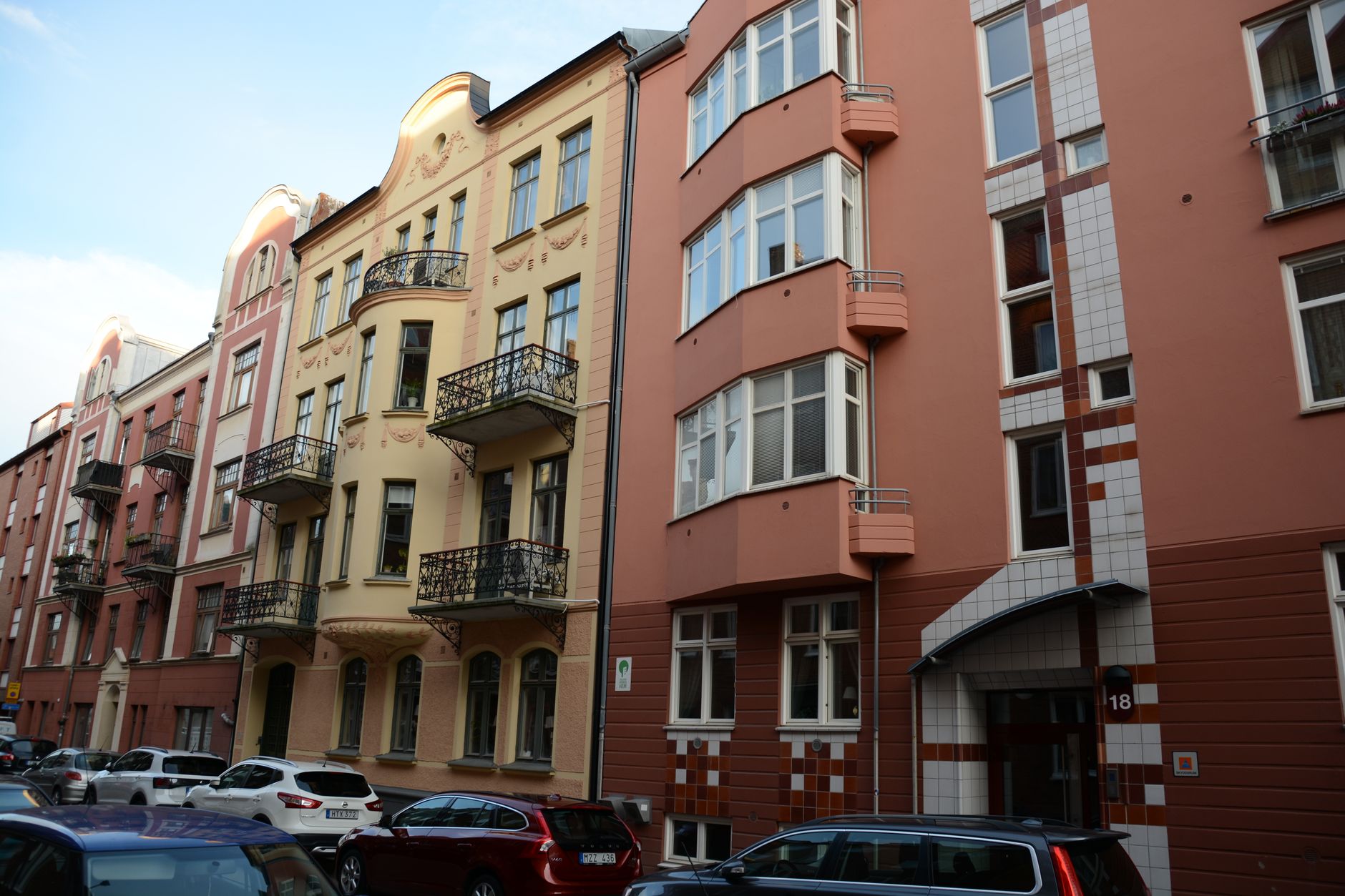 Aluguel de Quarto na Europa: Como Planejar os Custos por Cidade Charming urban street view with historic colorful buildings and parked cars.