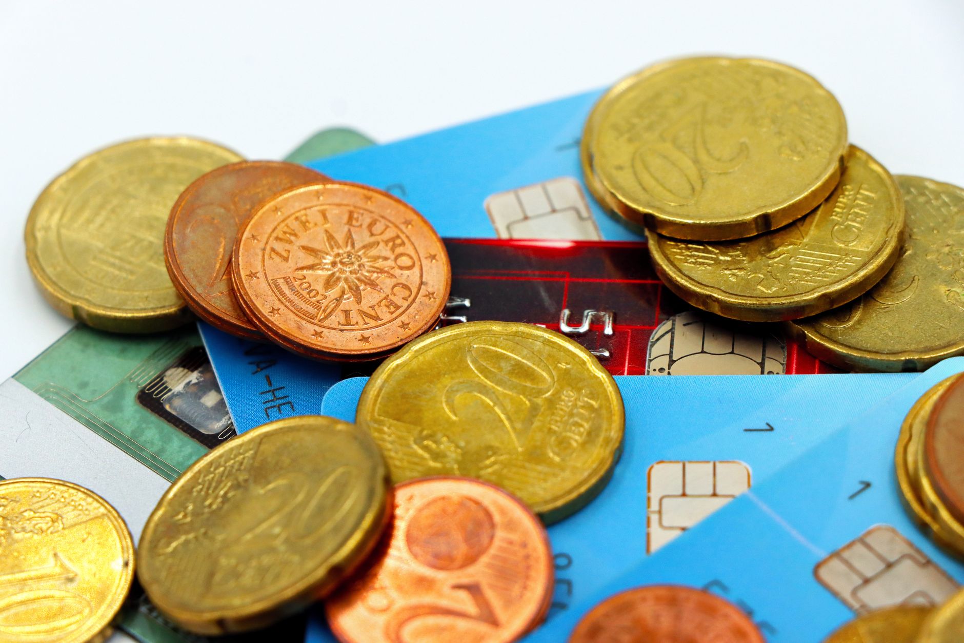 Pessoa segurando notas de euro e um cartão de crédito internacional próximo a um passaporte em uma mesa.
