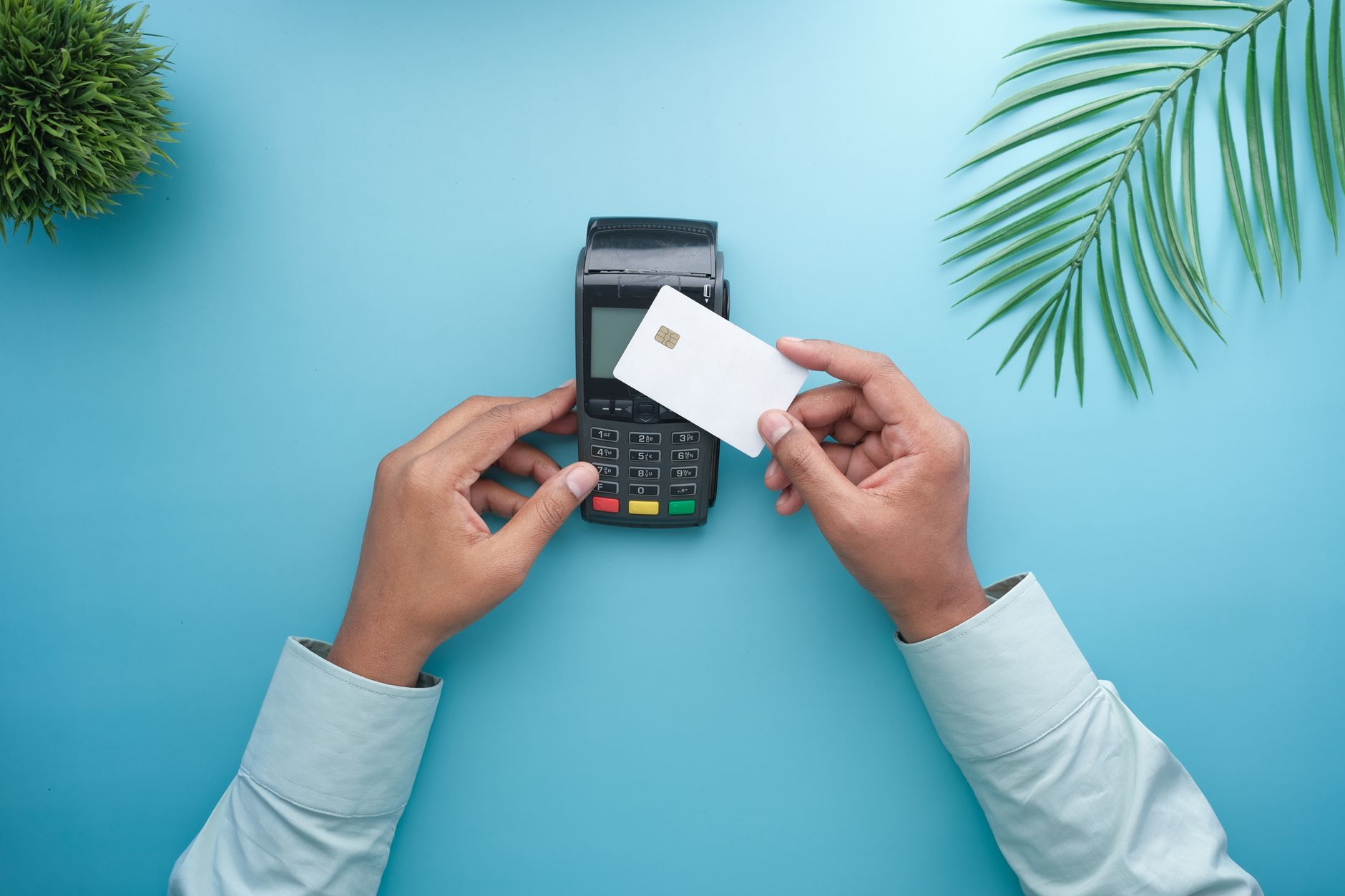 Como entender compras em euro na fatura do cartão? Hands using a contactless credit card on a payment terminal with a stylish minimal background.