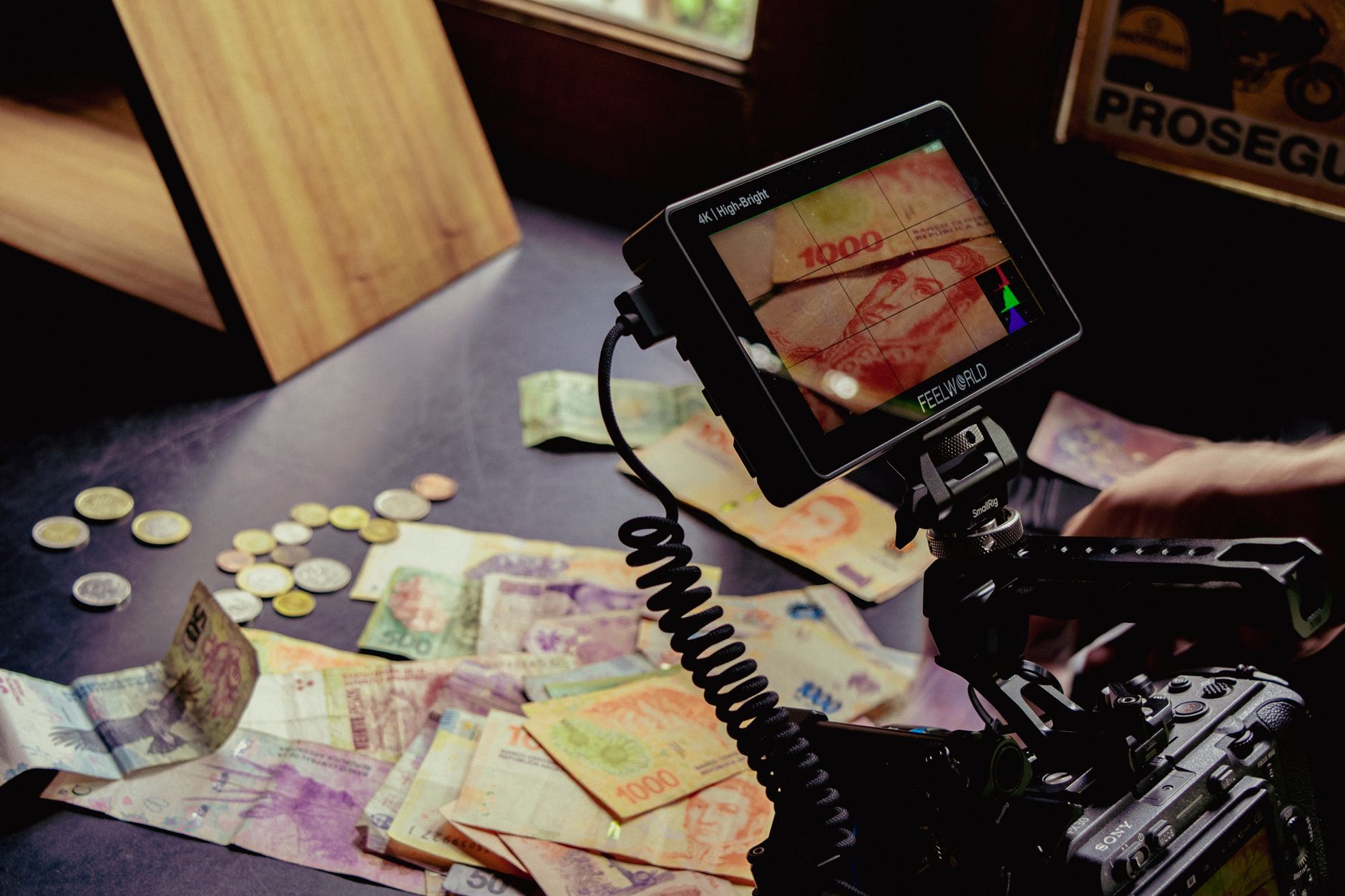 Cartão internacional para freelancer que recebe em dólar Camera setup capturing various global currencies on a table, detailed professional shot.