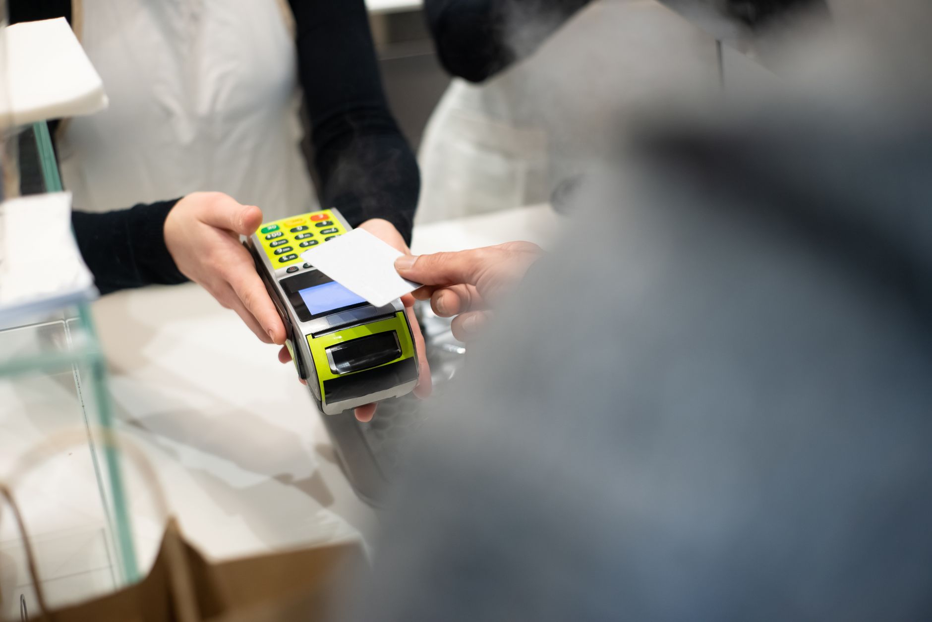 Pessoa pagando conta de restaurante na Europa utilizando cartão de débito em maquininha de cartão.