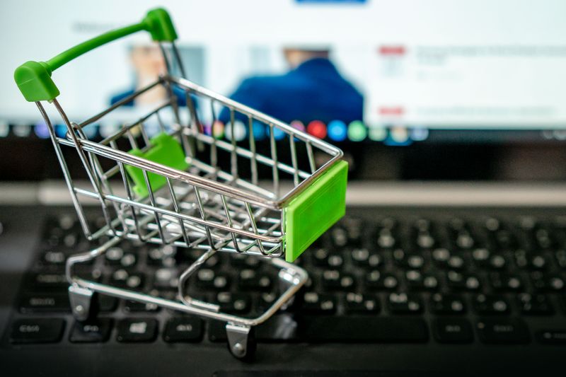 Cartão virtual em euro para compras online seguras Miniature shopping cart placed on a laptop keyboard, symbolizing online shopping.
