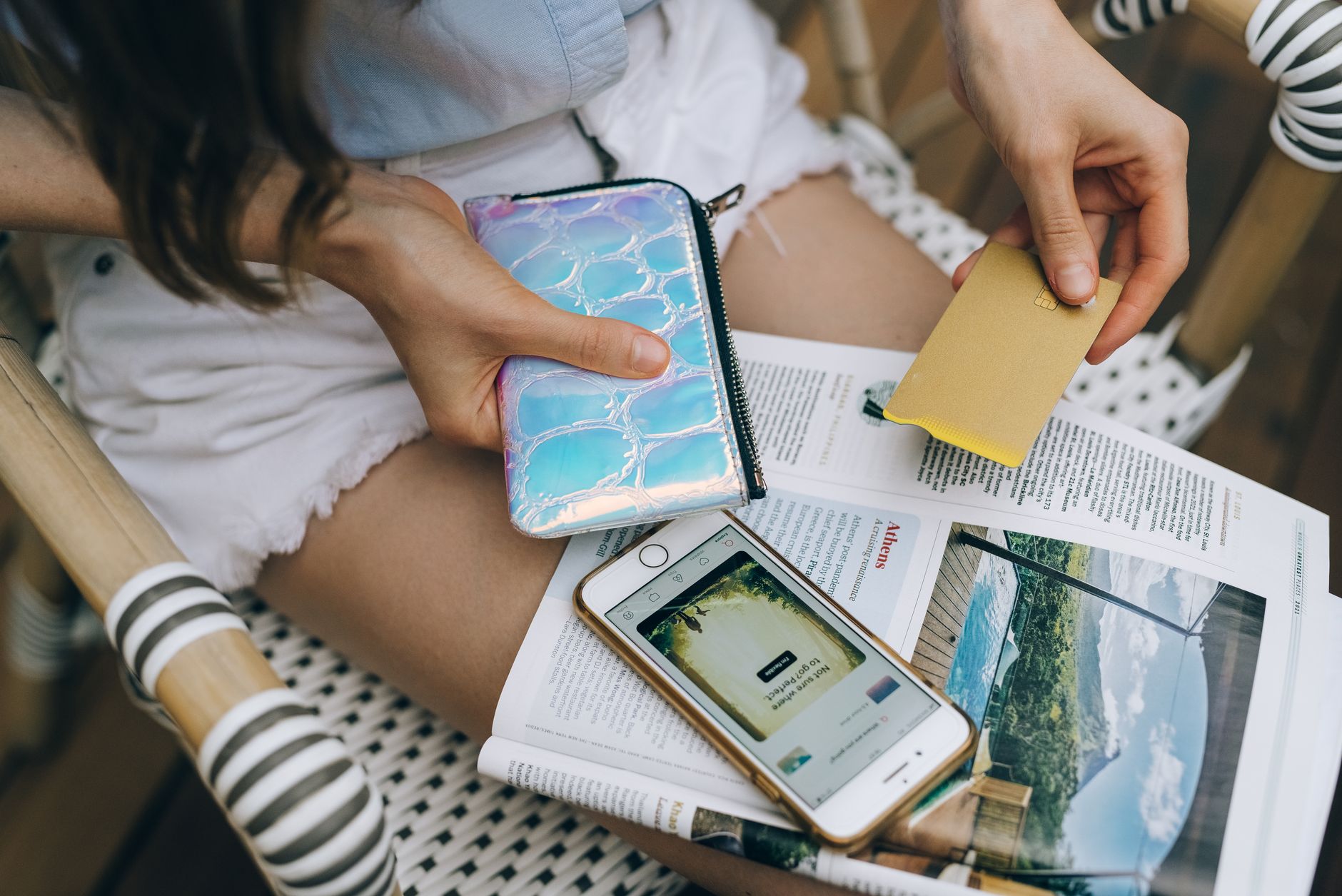 Cartão virtual funciona na Europa? Veja como usar A woman uses her smartphone and credit card for online shopping while sitting outdoors.