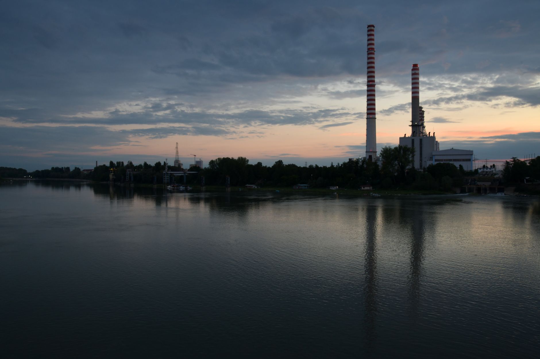 Scenic industrial landscape with chimneys and lake reflections during dusk in Revere, Italy.