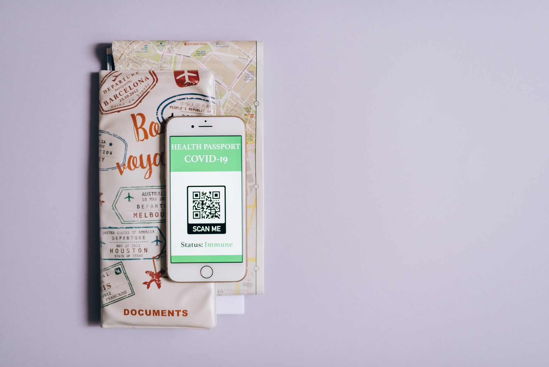 Como calcular quanto vai custar uma viagem em dólar Smartphone displaying a COVID-19 health passport with travel documents on a purple background.