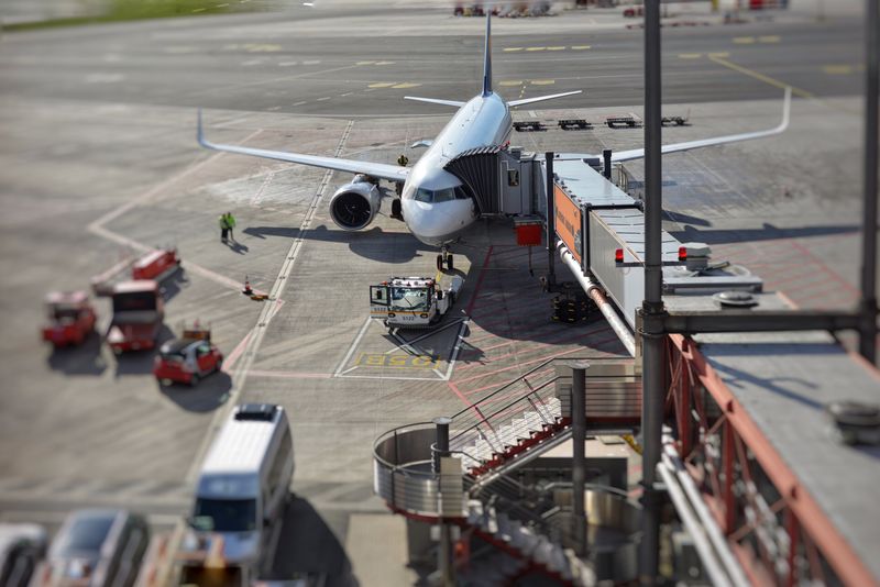Como declarar dinheiro em espécie ao voltar de viagem A bustling airport scene with an airplane on the tarmac being prepared for departure.
