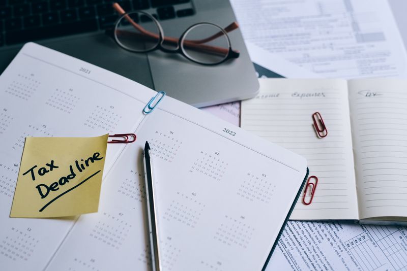 Como declarar conta internacional de fintech no Imposto de Renda A desk with a planner, sticky note marked 'Tax Deadline', and paperwork, indicating financial planning.