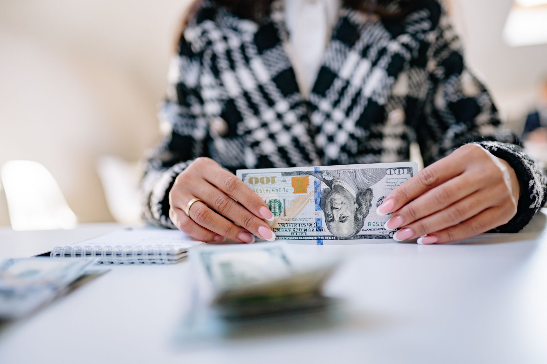 Pessoa conferindo cédulas de dólar e documentos em uma mesa