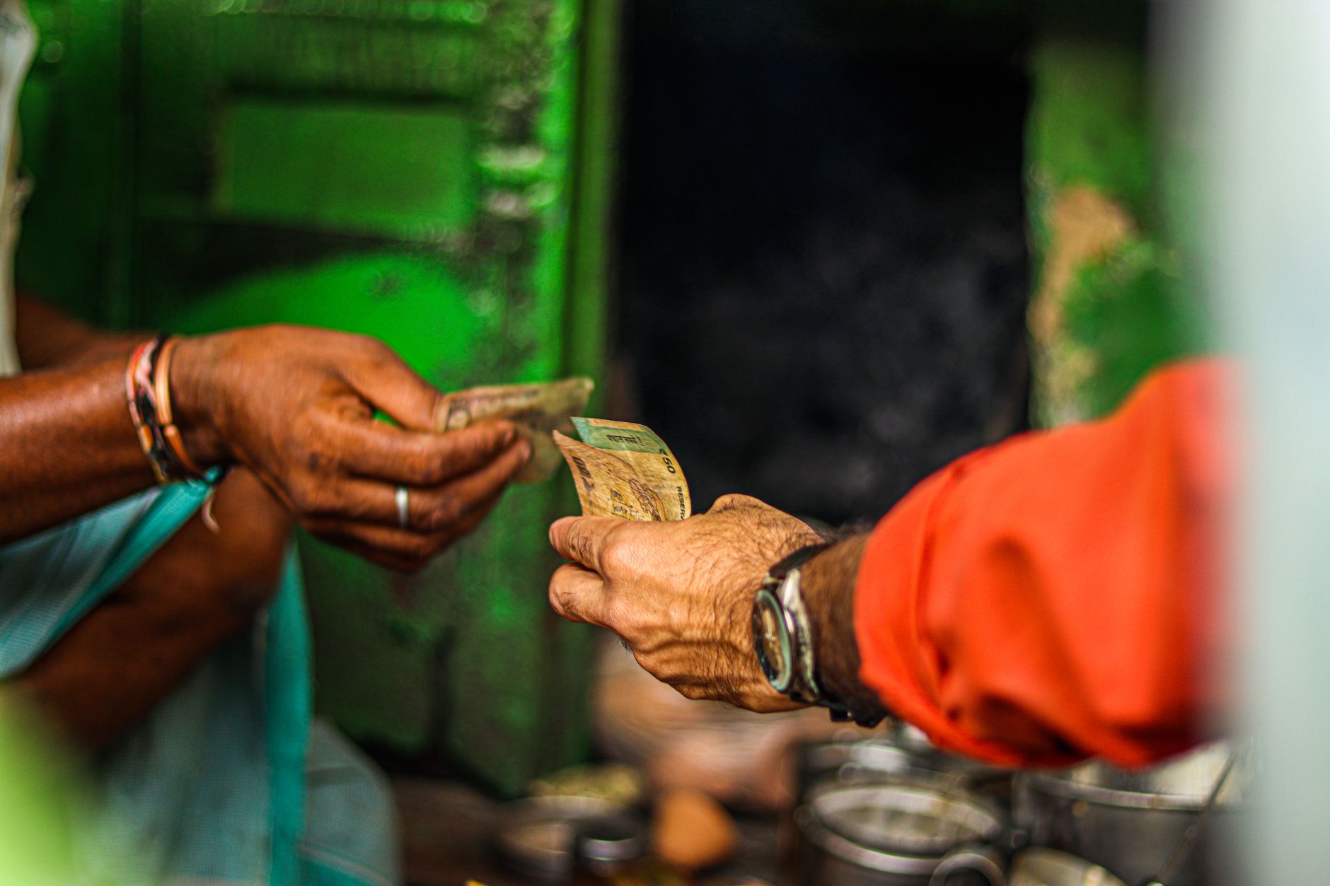 Como funciona a compra e venda de dólar em bancos A close-up shot of two people exchanging currency in an outdoor market setting.