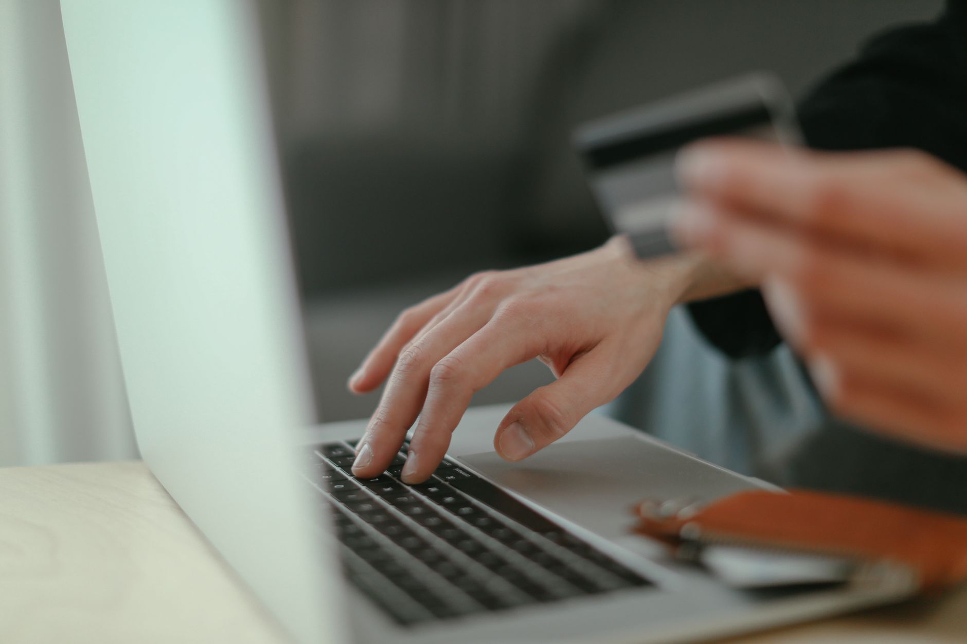 Pessoa segurando um cartão de crédito em frente a um computador navegando em um site de compras internacionais.