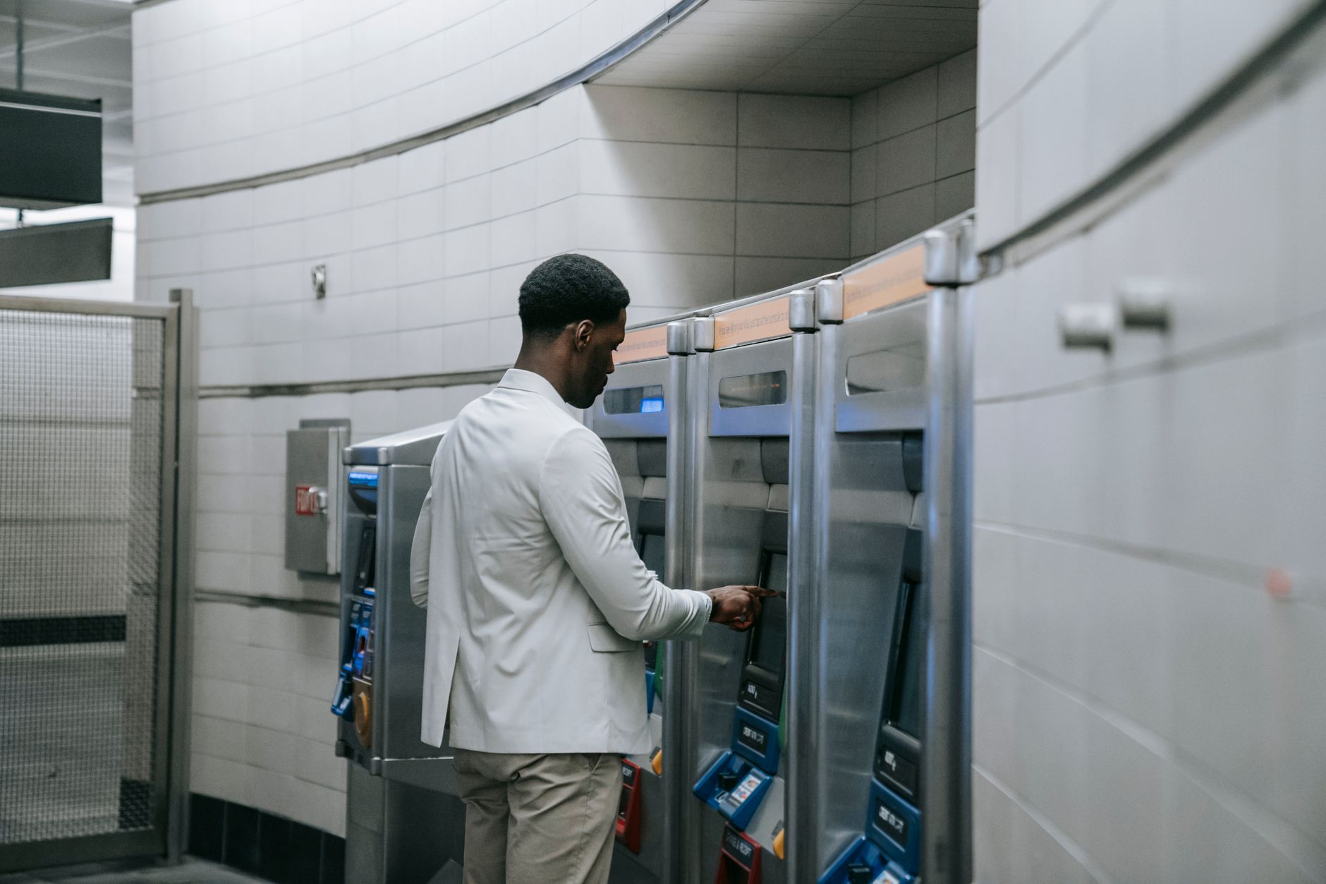 A man operating a ticket machine in a modern subway station, symbolizing urban public transport.