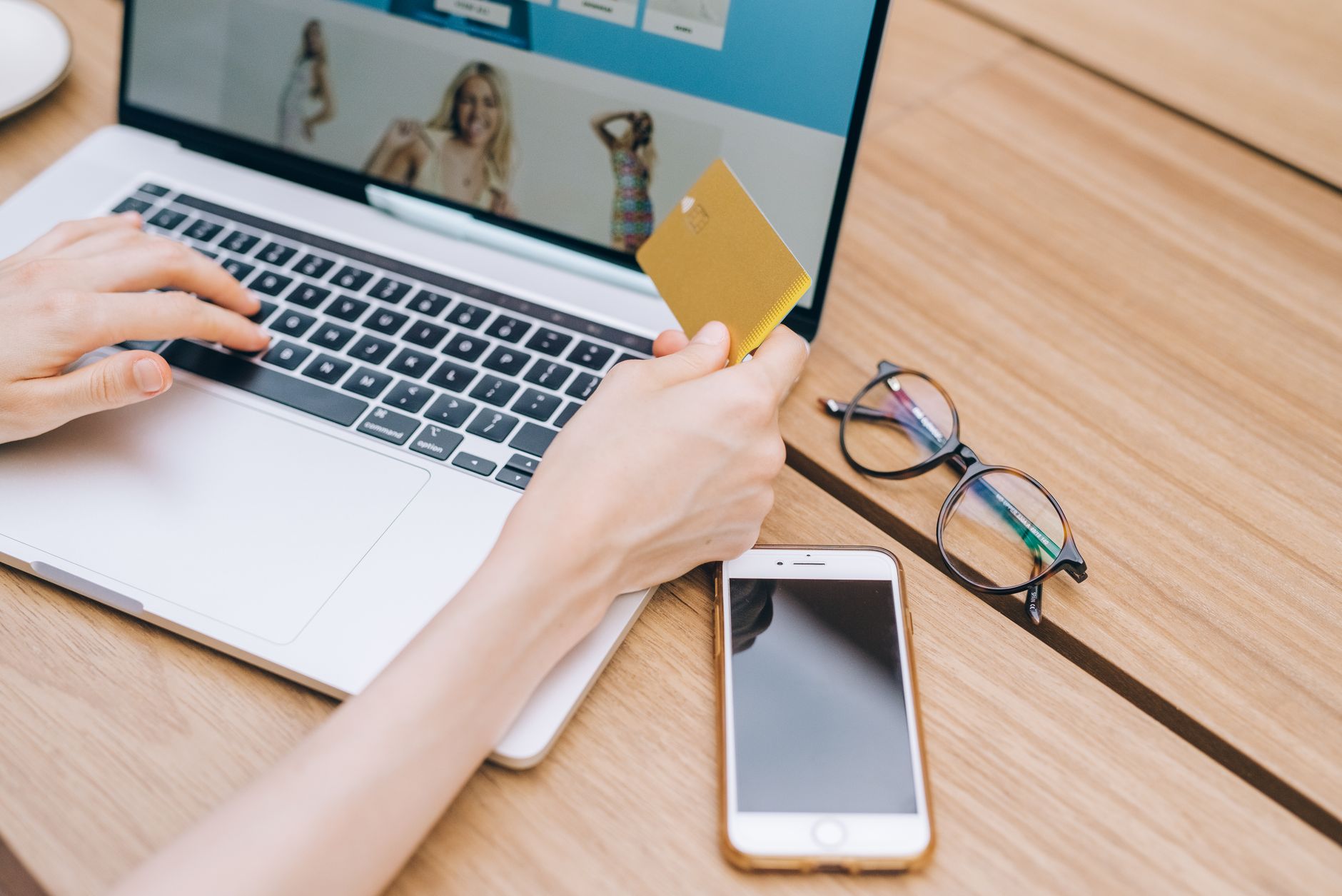Pessoa conferindo o cartão e o celular enquanto organiza uma compra internacional em uma mesa