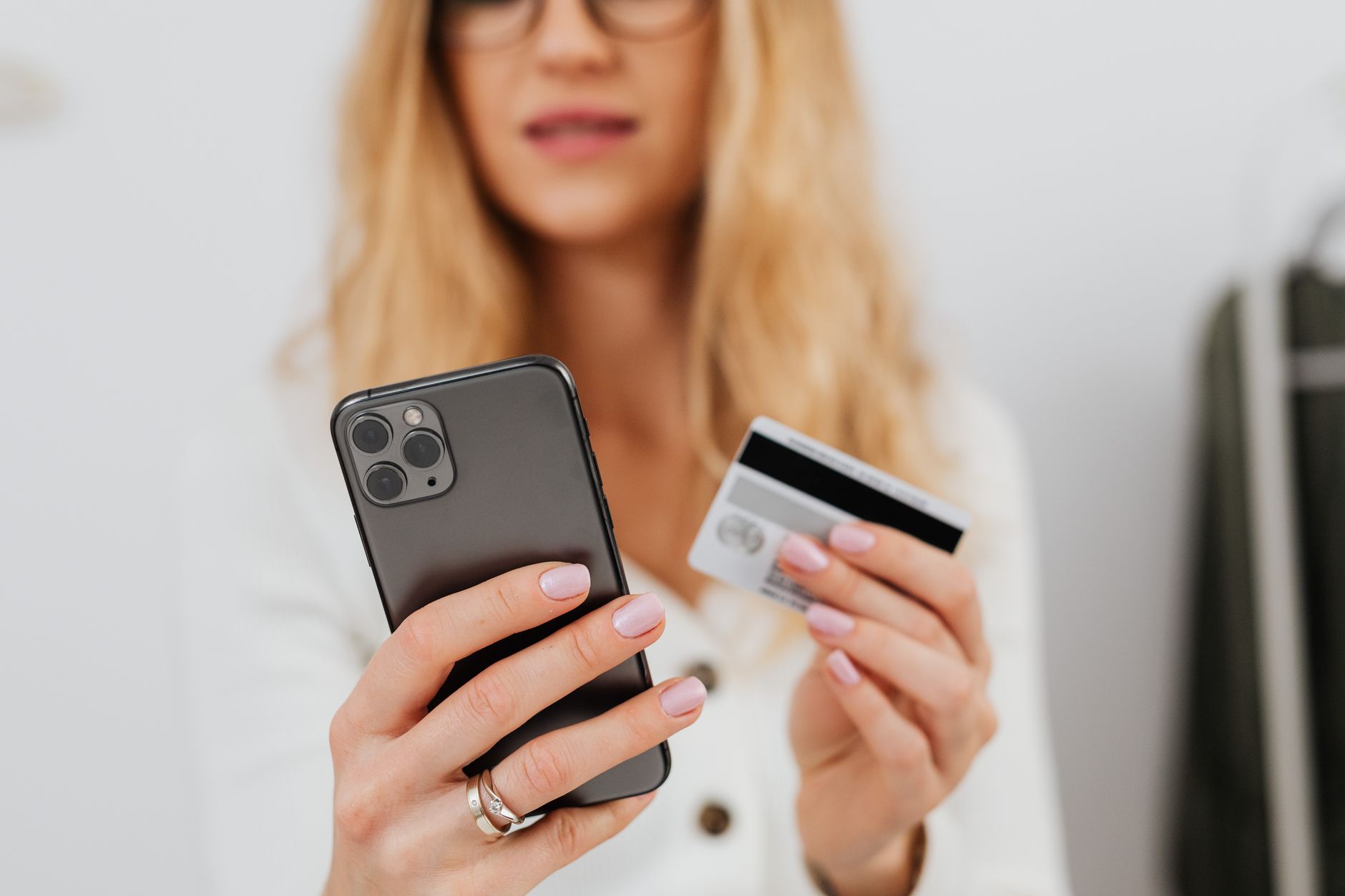 Pessoa segurando cartão de crédito internacional e celular com aplicativo financeiro aberto em uma mesa de trabalho.