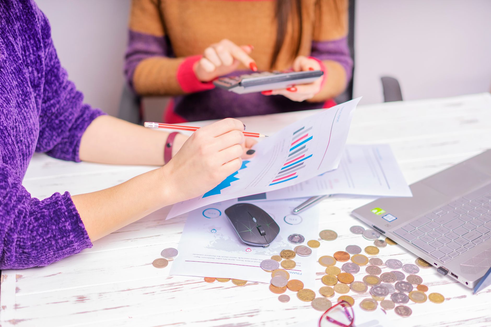 Pessoa analisando gráficos de câmbio e documentos financeiros em uma mesa