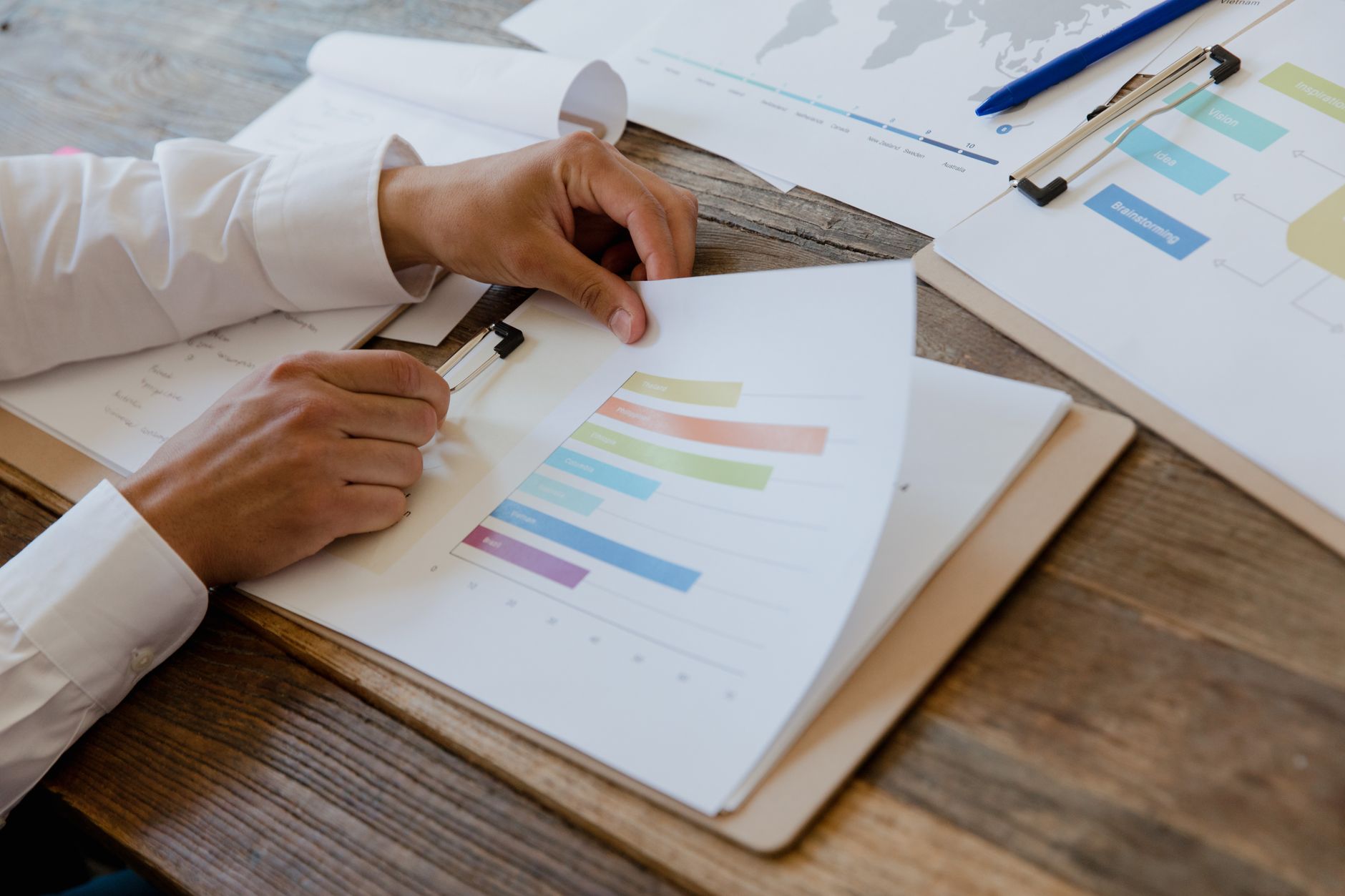 Pessoa analisando contrato, extratos e comprovantes de pagamento em dólar sobre uma mesa.
