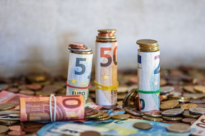 Como Guardar Comprovantes de Câmbio e Investimento no Exterior Close-up of rolled Euro banknotes and coins on a table, symbolizing finance and savings.