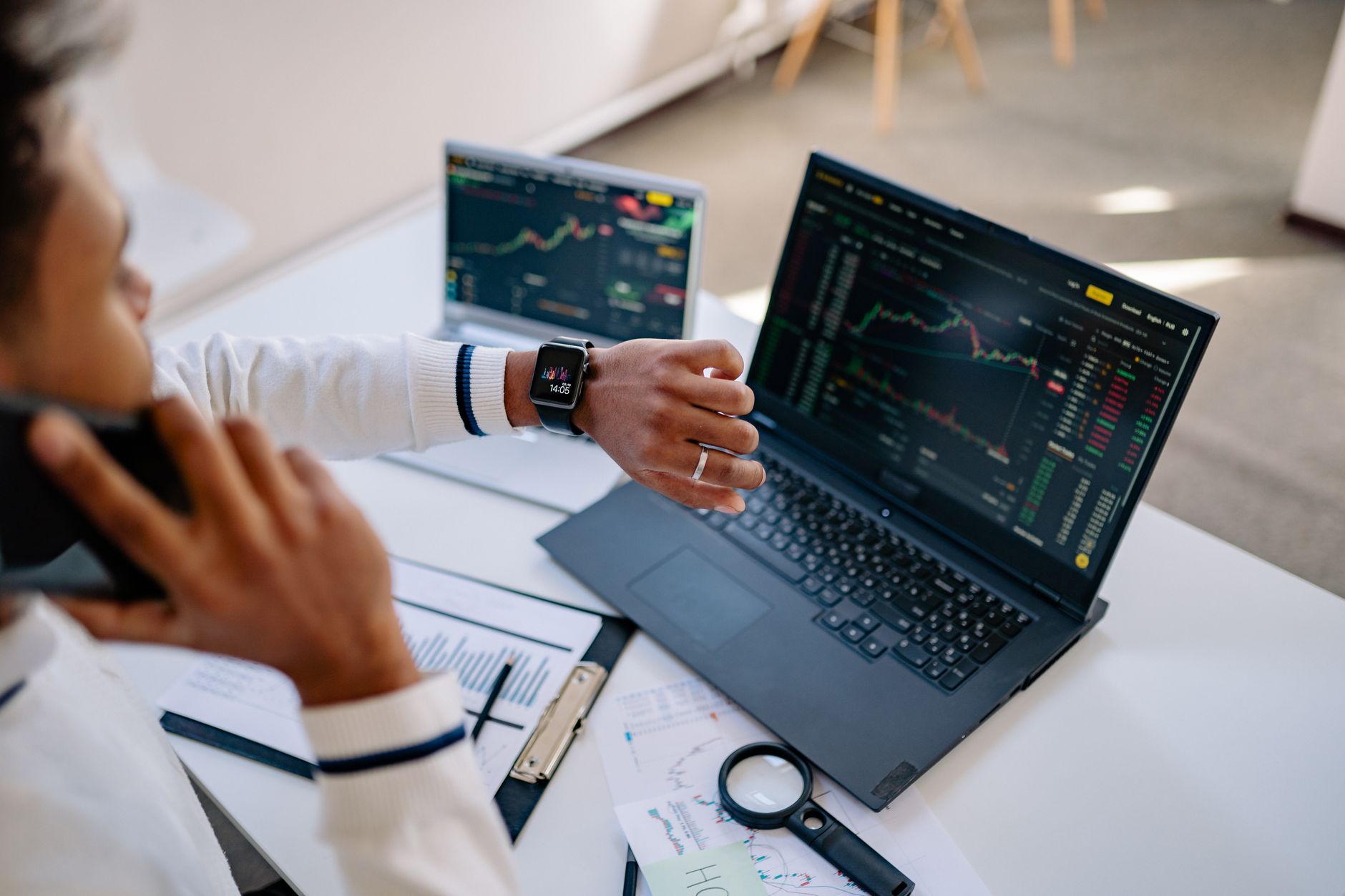 Executivo analisando gráficos financeiros e cotações de moedas em um laptop.