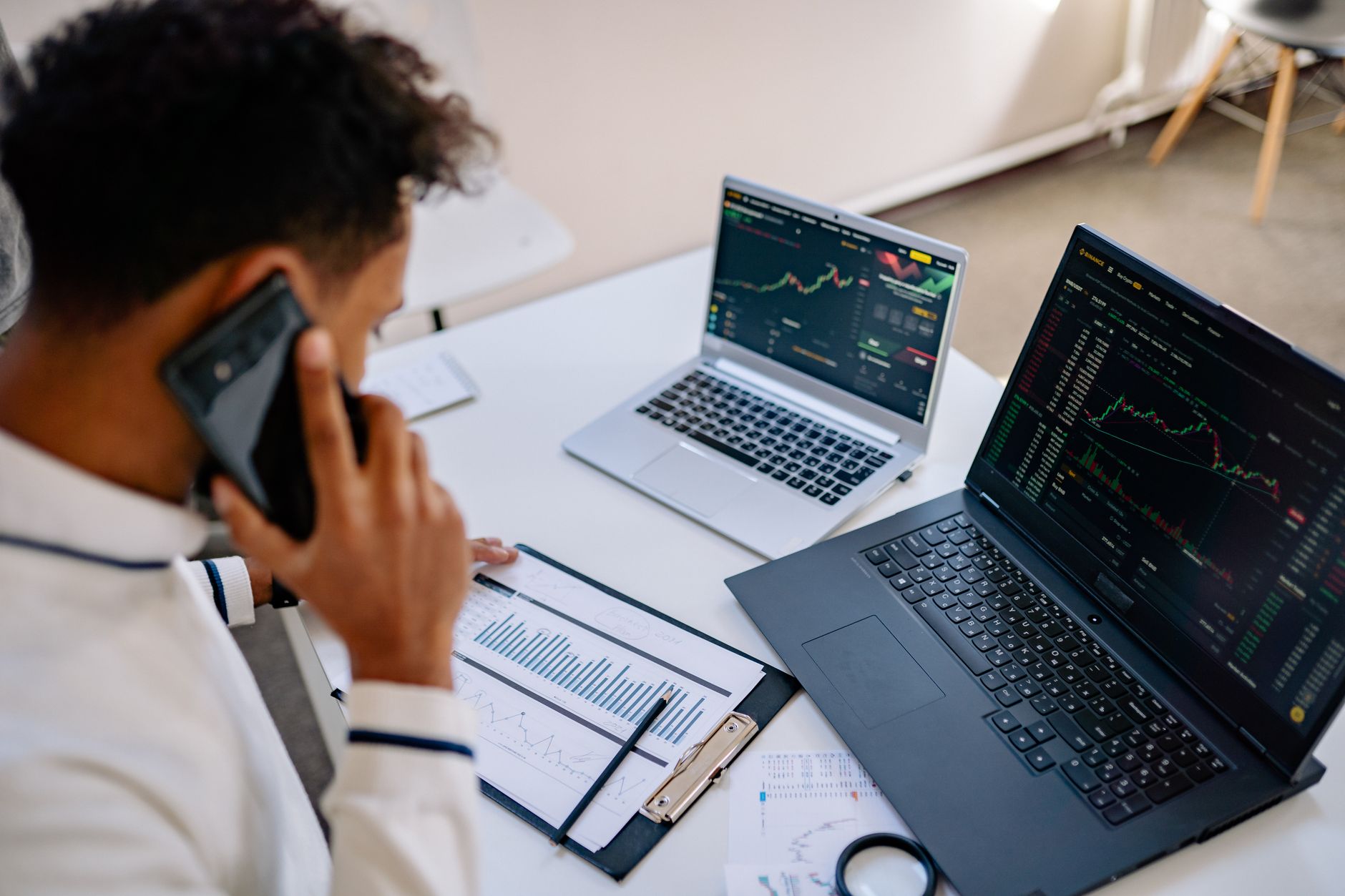 Investidor analisando gráfico de carteira de investimentos no computador com notas de dólar e euro sobre a mesa