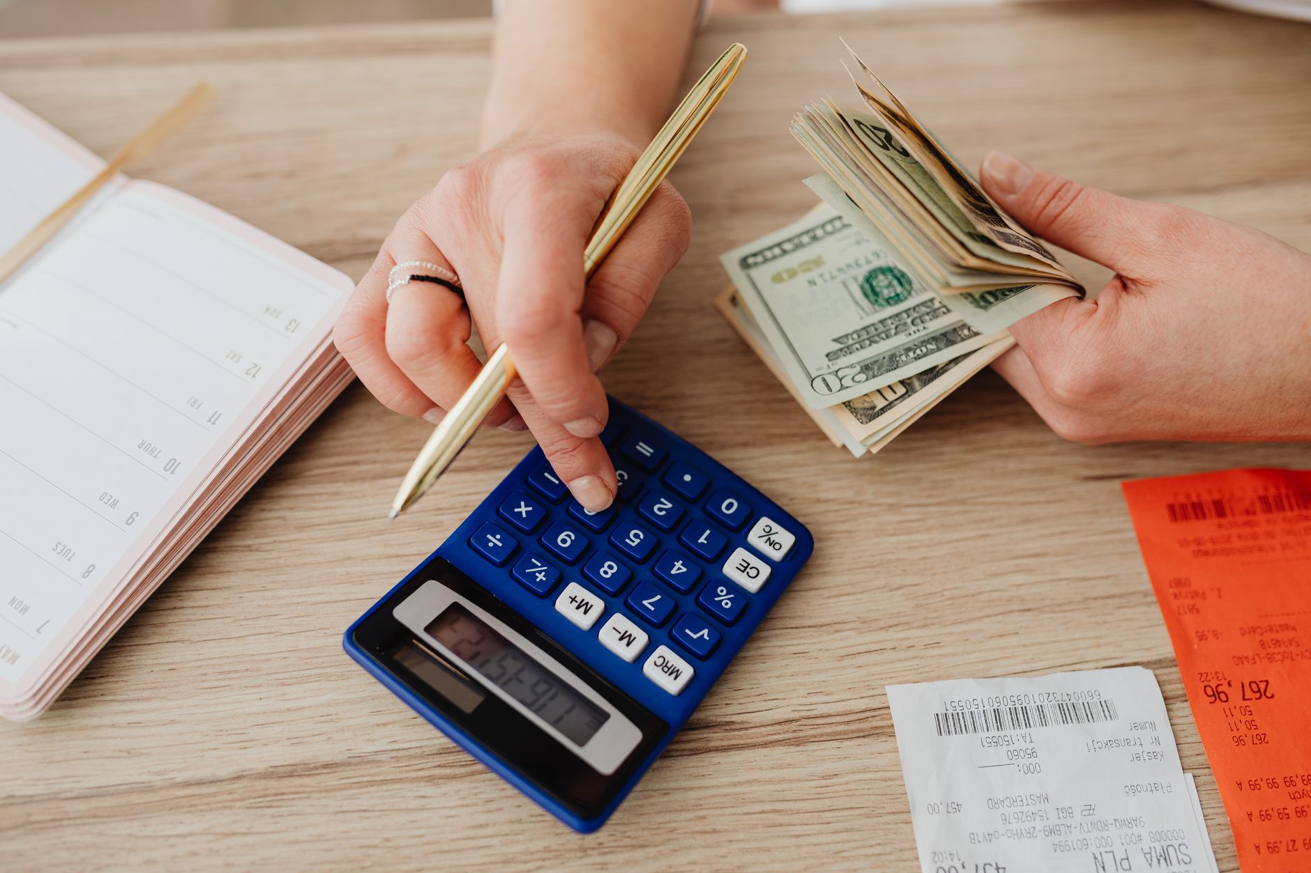 Hands handling cash and calculator for budget planning. Modern financial scene.