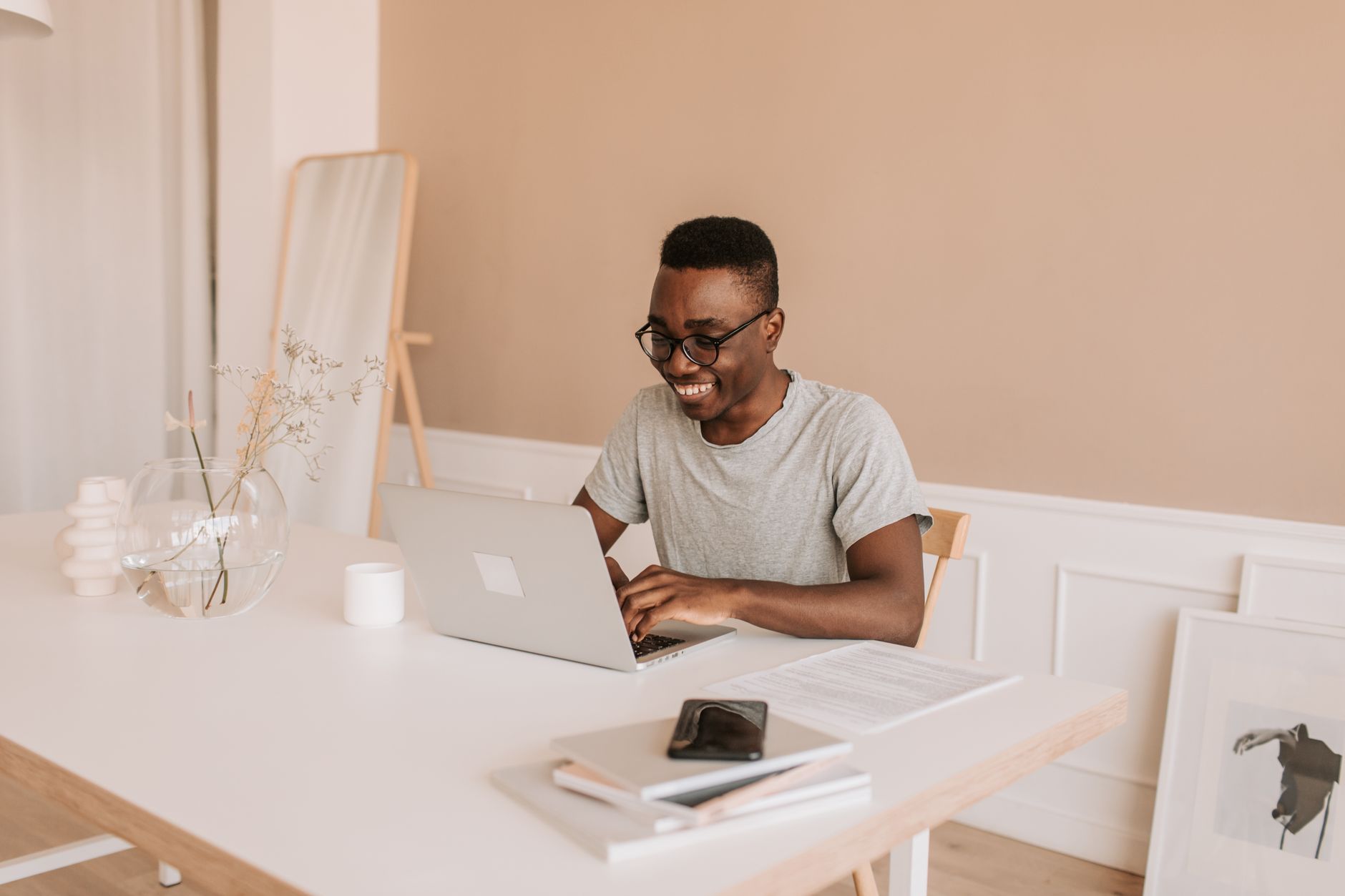 Como se planejar financeiramente para um intercâmbio Happy young man typing on laptop in bright modern home office, enjoying his work.