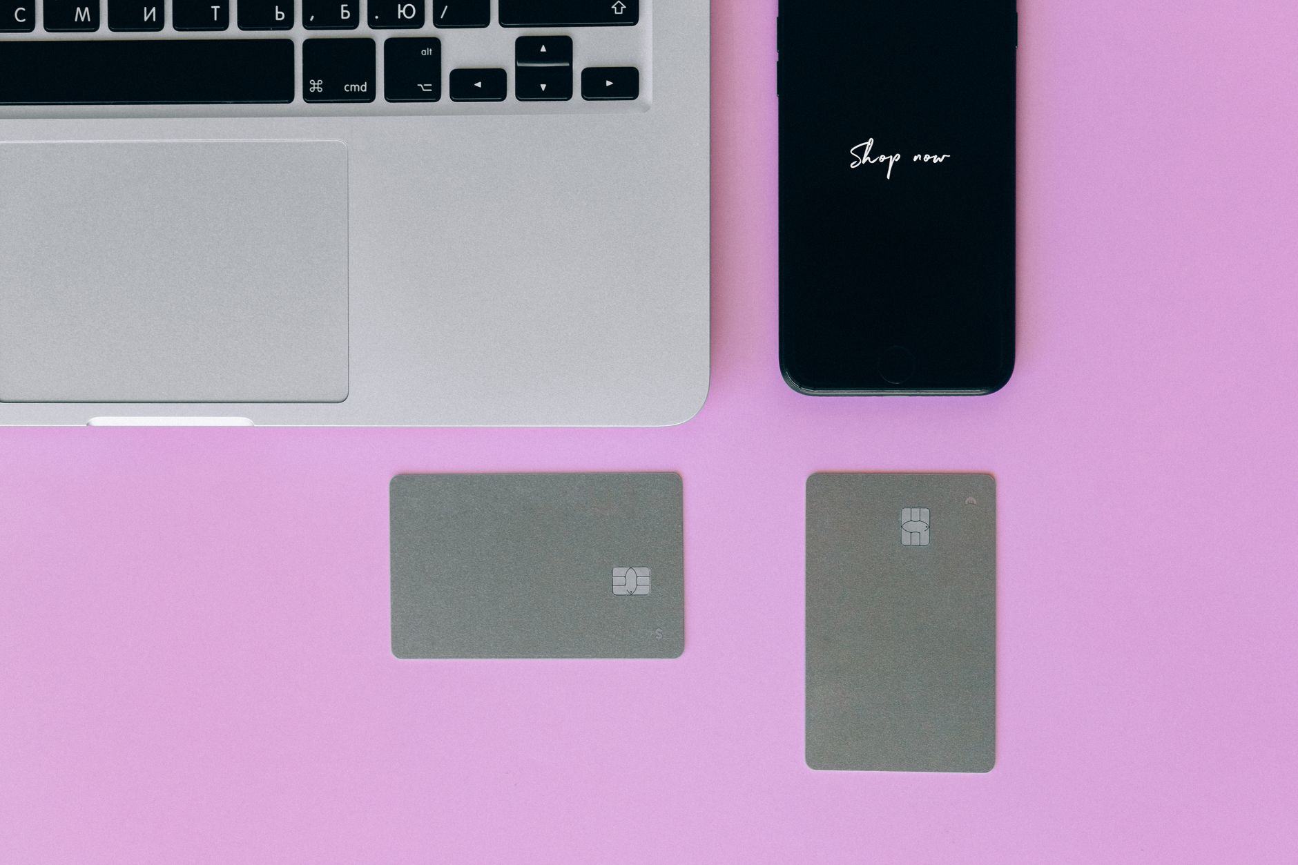 Comprar dólar hoje ou esperar? Veja como tomar a decisão Laptop, cards, and smartphone on pink background for online shopping.