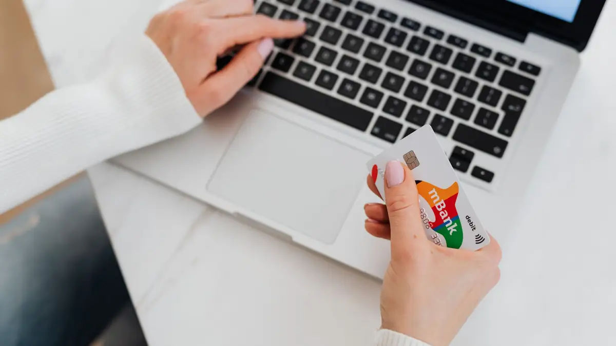 Pessoa usando notebook e cartão de crédito para compras online