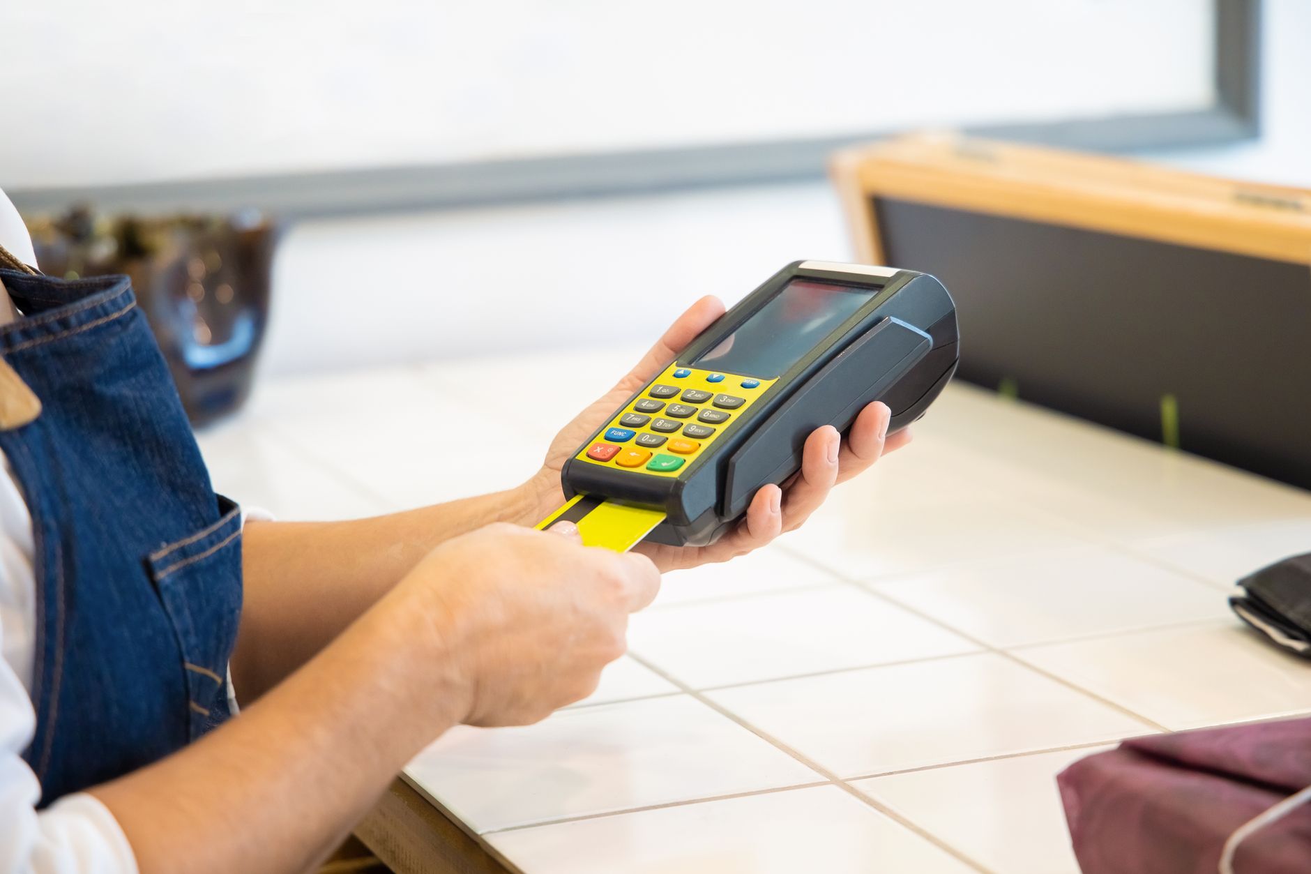 Conta conjunta em moeda estrangeira para casal: como declarar Close-up of hands operating a credit card POS machine in a commercial setting.