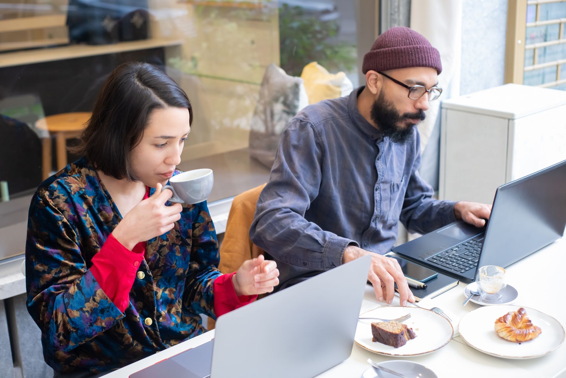 Casal jovem sentado em uma mesa de café na Europa organizando contas e cartão bancário em um notebook.