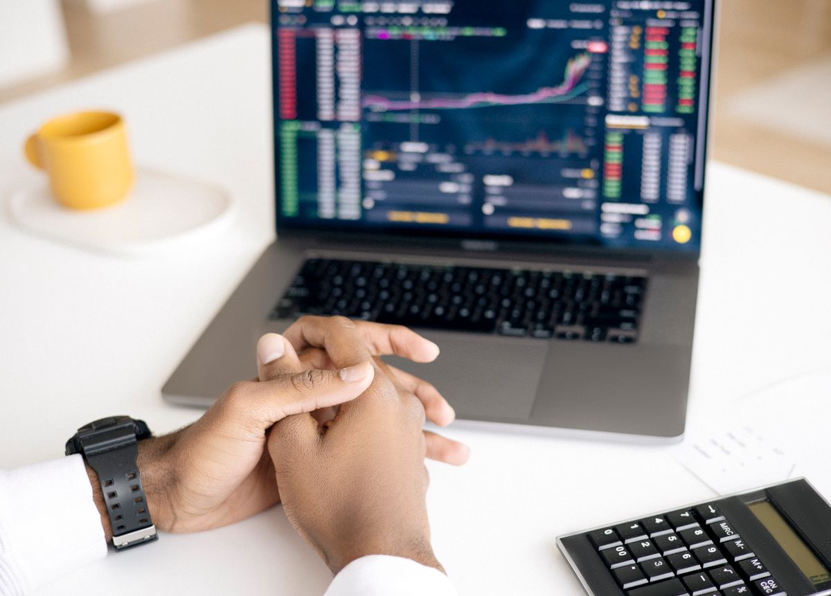 Pessoa analisando cotações de moedas no computador e na calculadora
