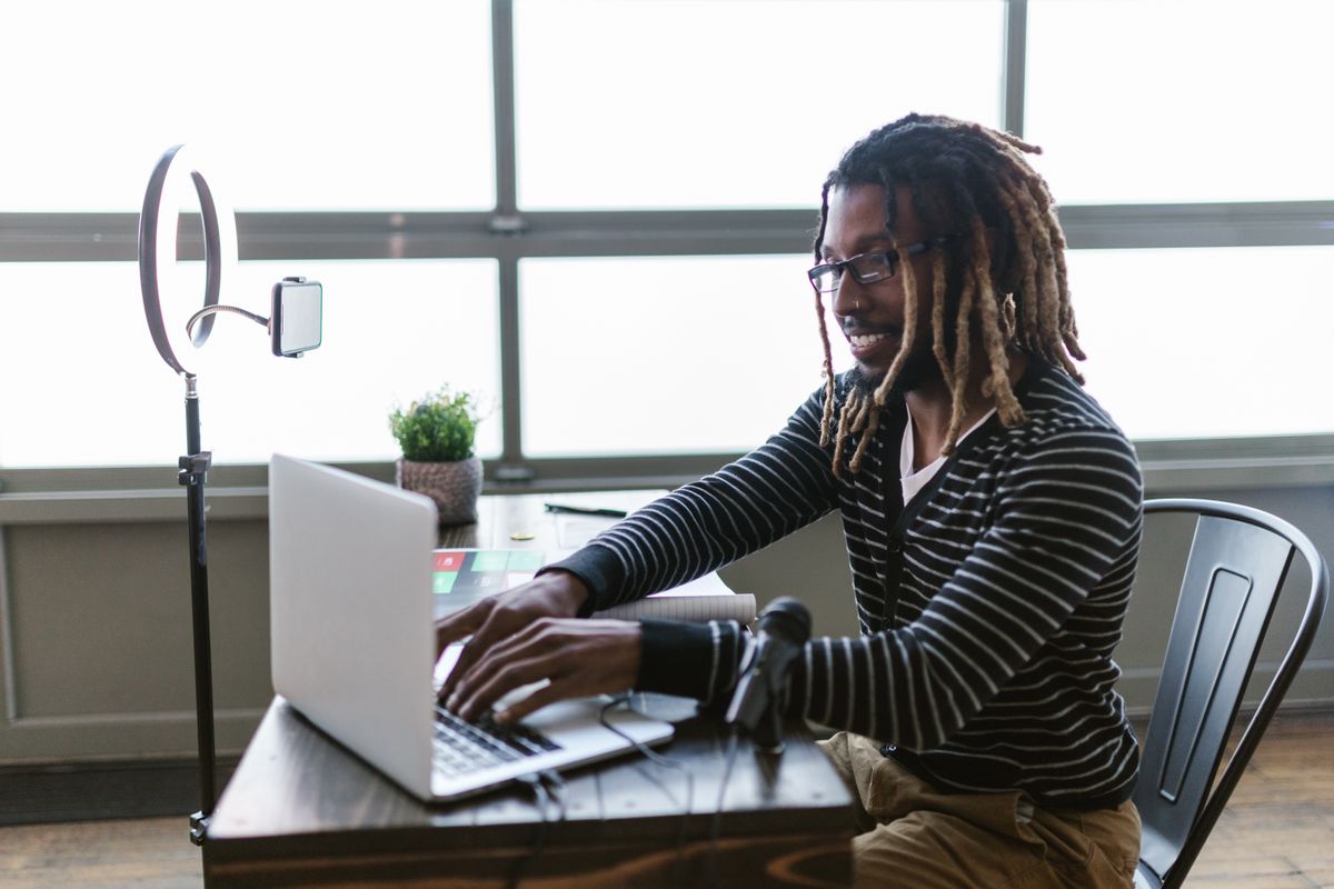 Pessoa trabalhando no notebook em escritório com dados de transferência financeira na tela.