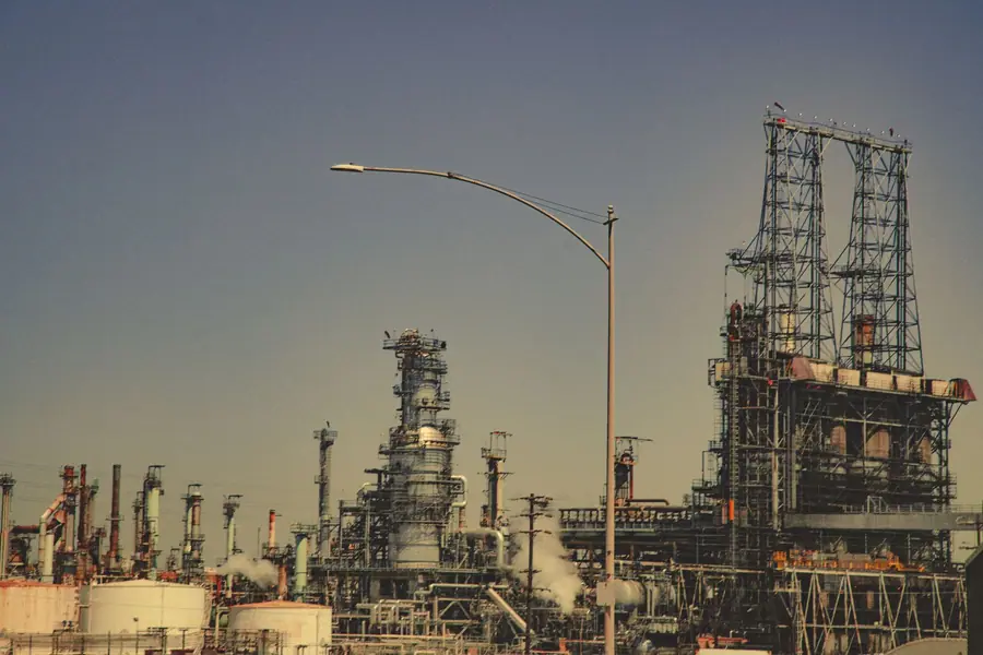 Grande refinaria de petróleo com tubulações e torres sob céu azul Grande refinaria de petróleo com tubulações e torres sob céu azul