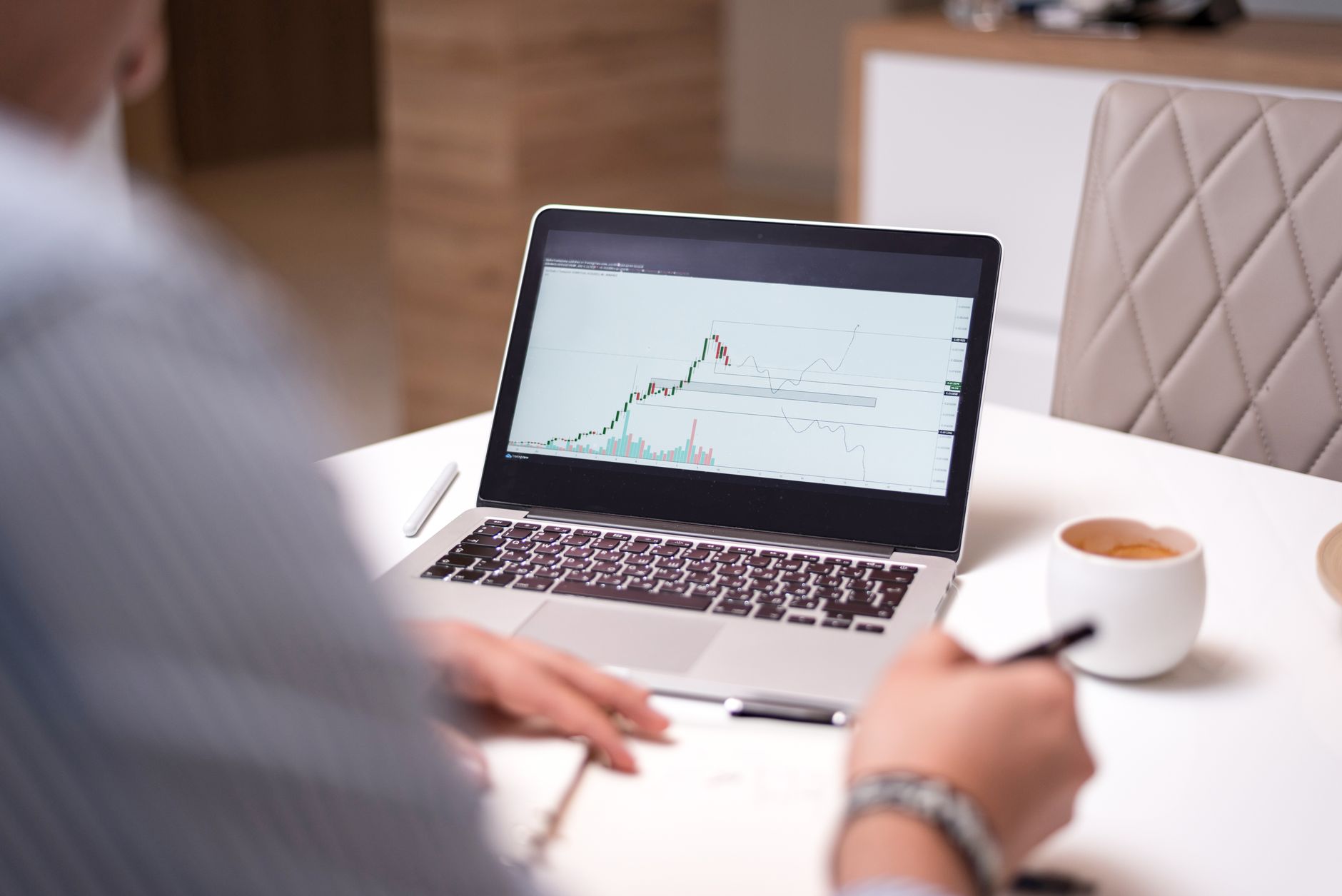 Pessoa analisando gráficos do mercado financeiro em um monitor de computador em um escritório.