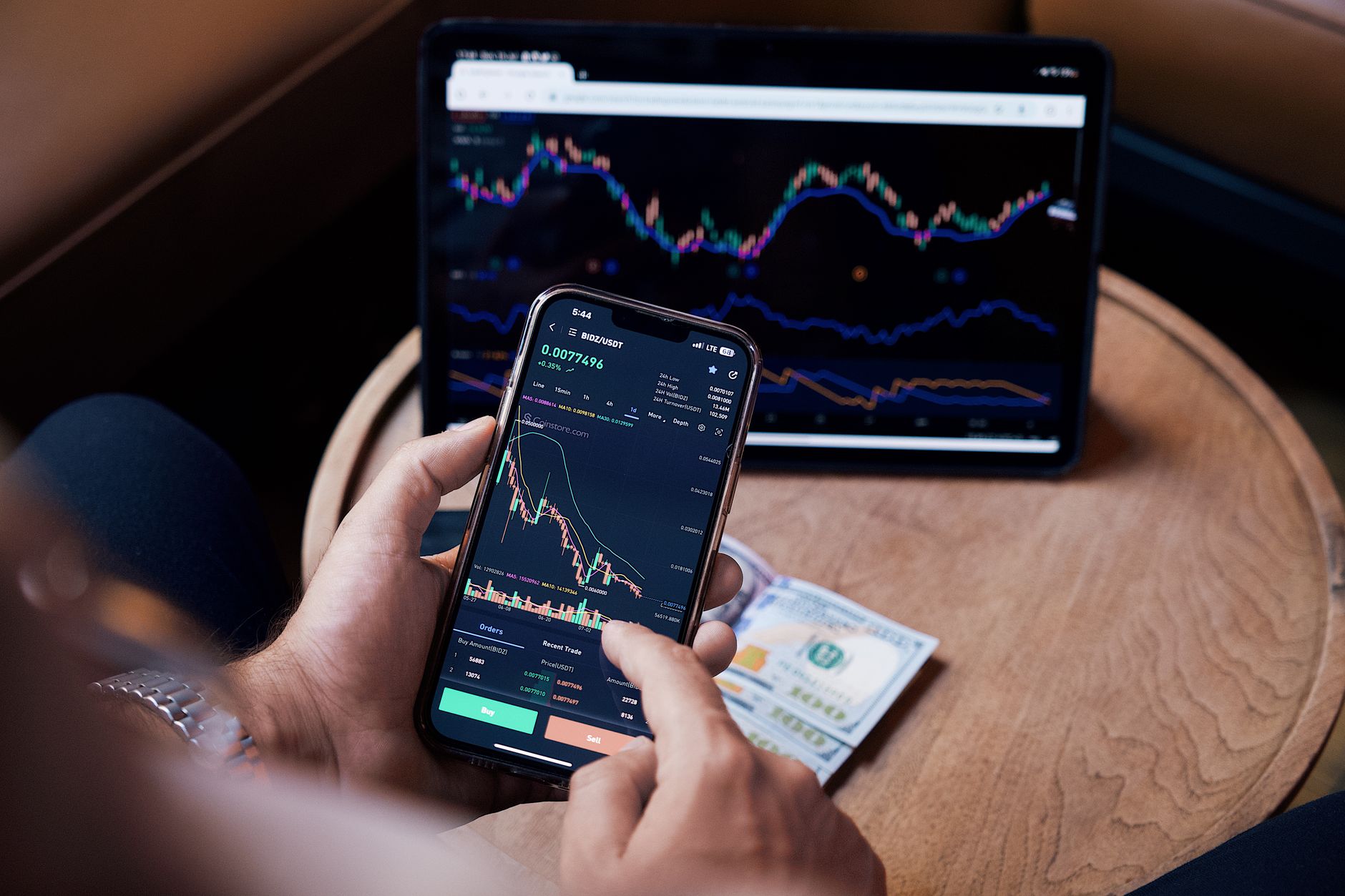 Dólar futuro na B3 serve para o consumidor comum? Close-up of a person trading stocks using a smartphone and a tablet.