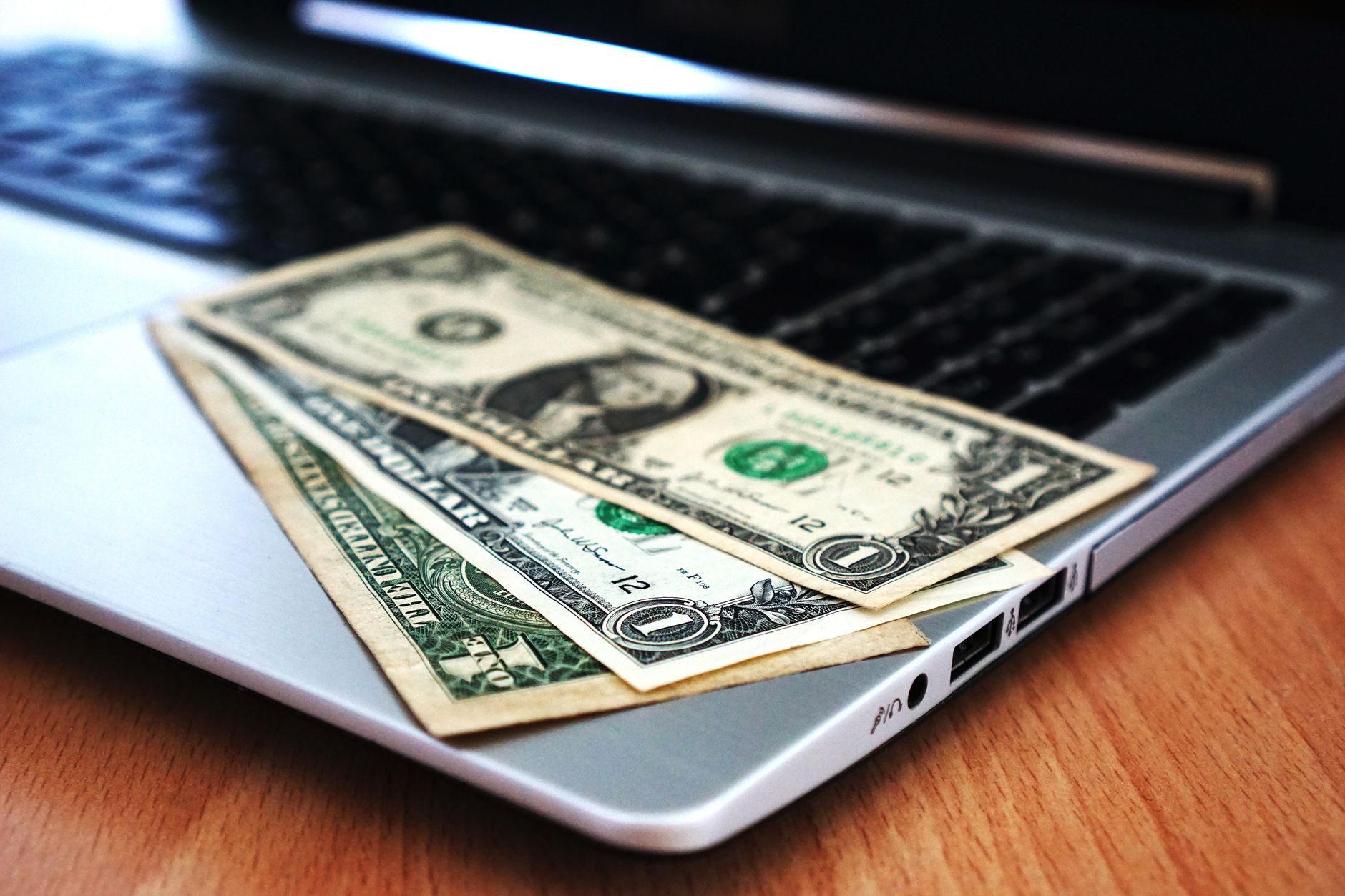 Pessoa utilizando um laptop e celular para realizar transferência bancária internacional.