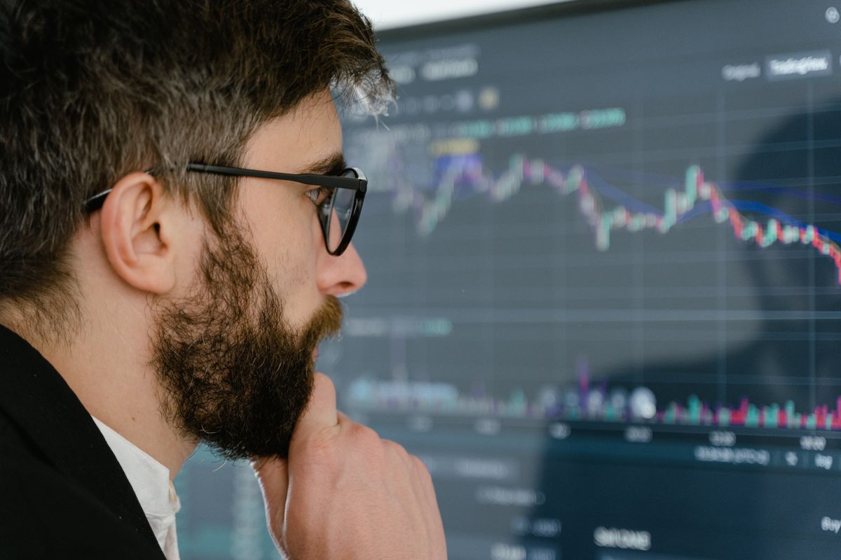 Pessoa preocupada analisando gráficos de cotação cambial na tela do computador.