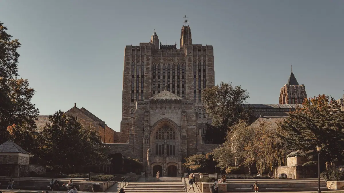 Prédios neoclássicos de uma universidade americana com gramados e estudantes