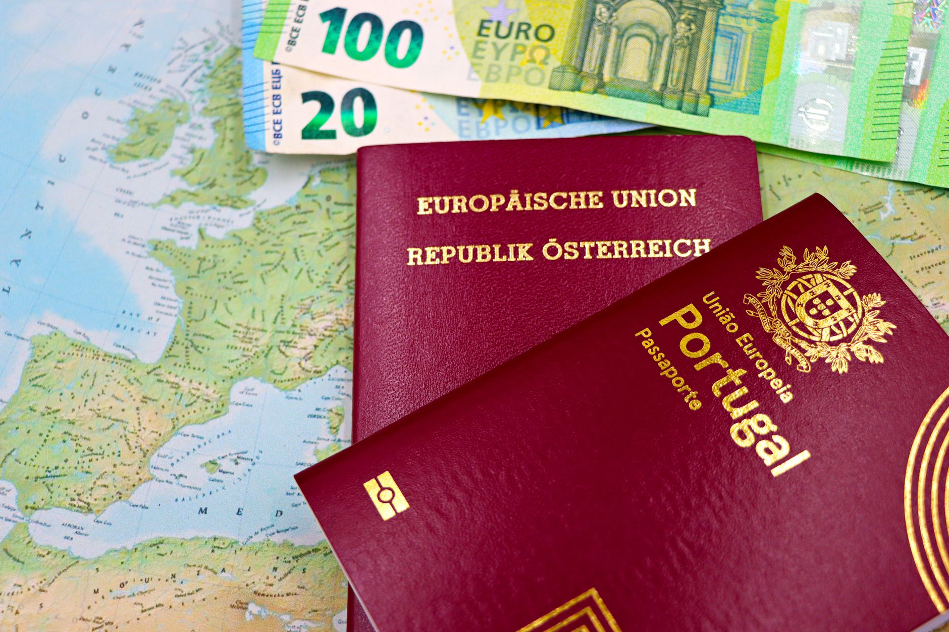 Pessoa segurando notas de euro e passaporte em cima de uma mesa de madeira.