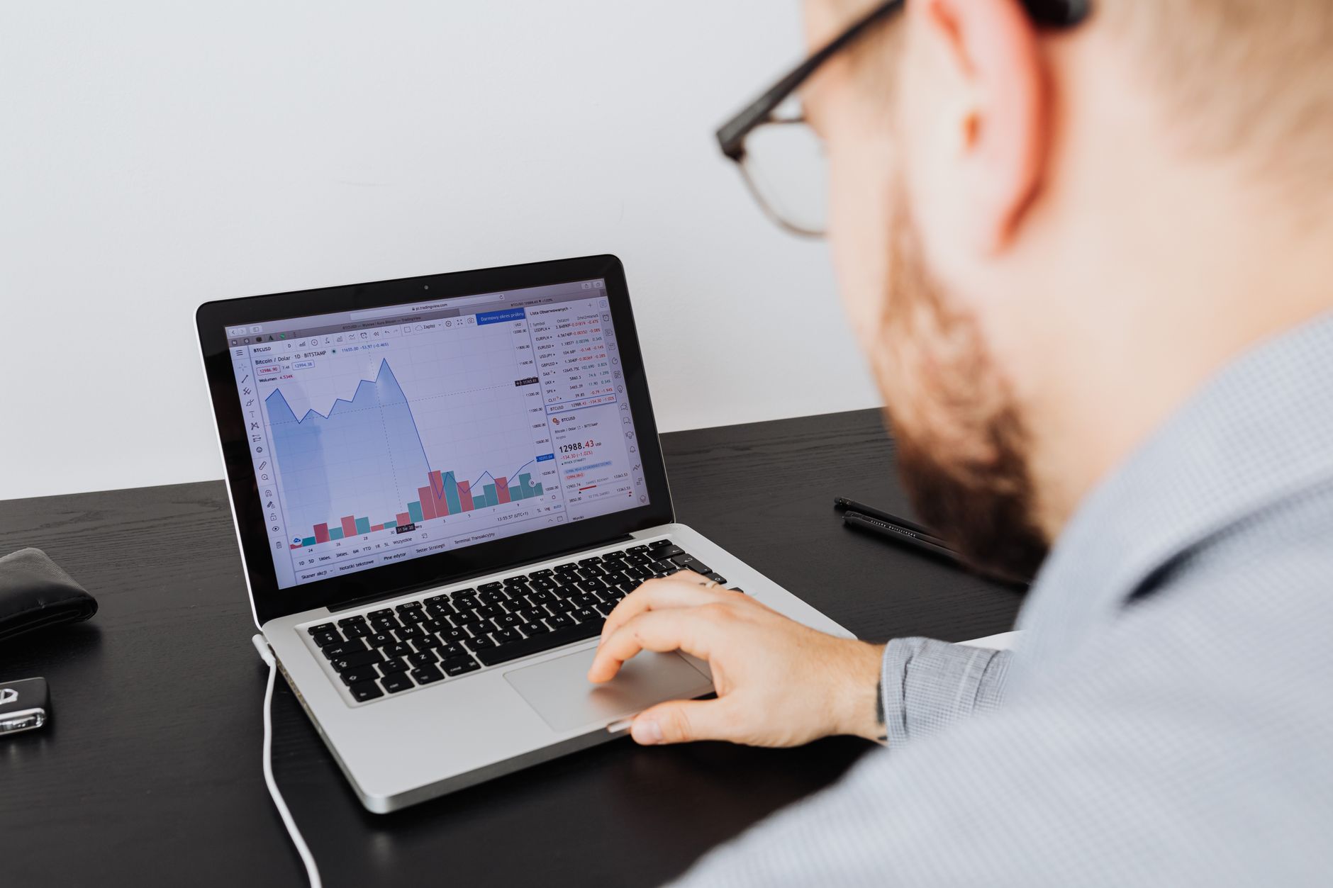 Pessoa utilizando laptop para analisar gráficos do mercado financeiro europeu ao lado de notas de euro e passaporte.