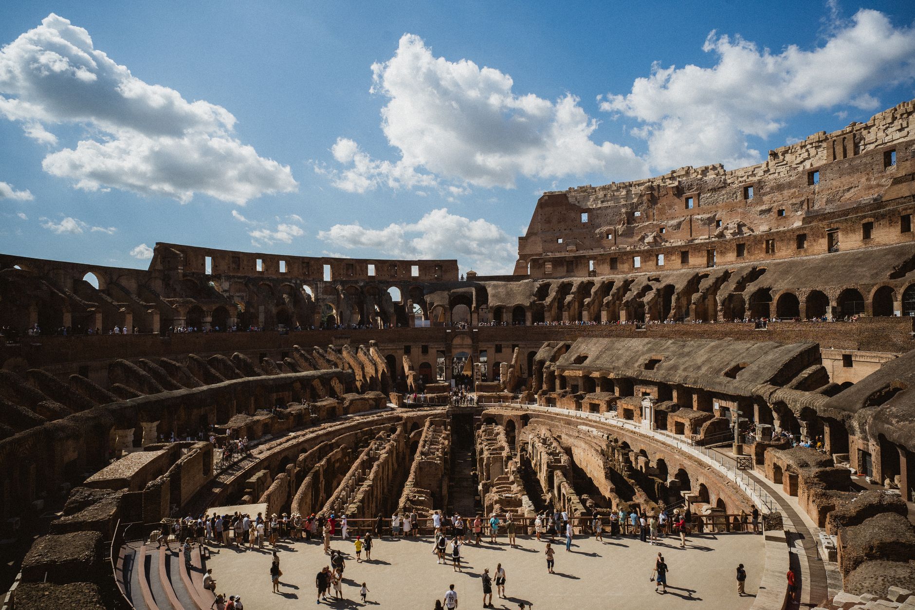 Pessoa segurando moedas e notas de euro com o Coliseu ao fundo em Roma.